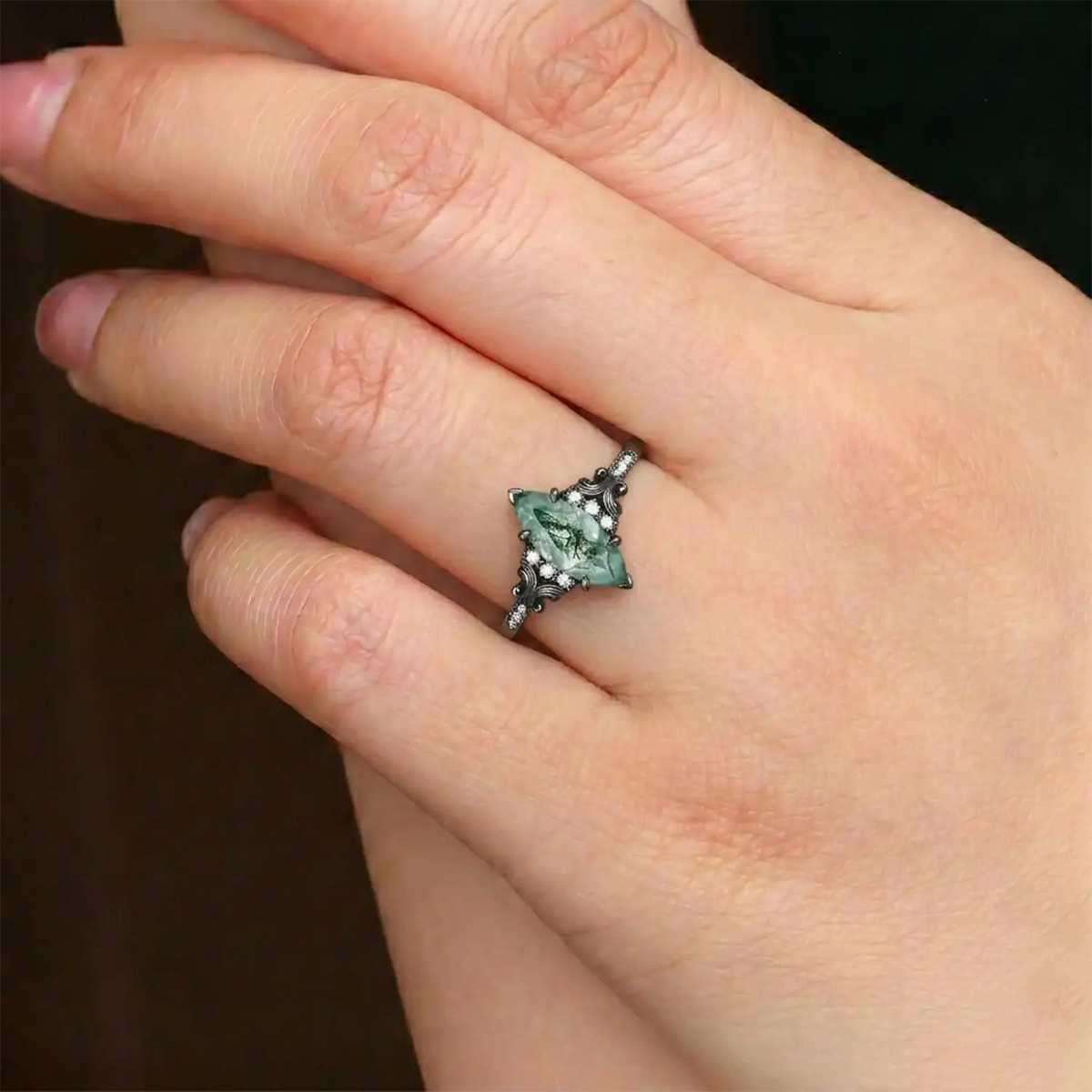 Woman wearing marquise moss agate black gold engagement ring vintage moissanite cluster