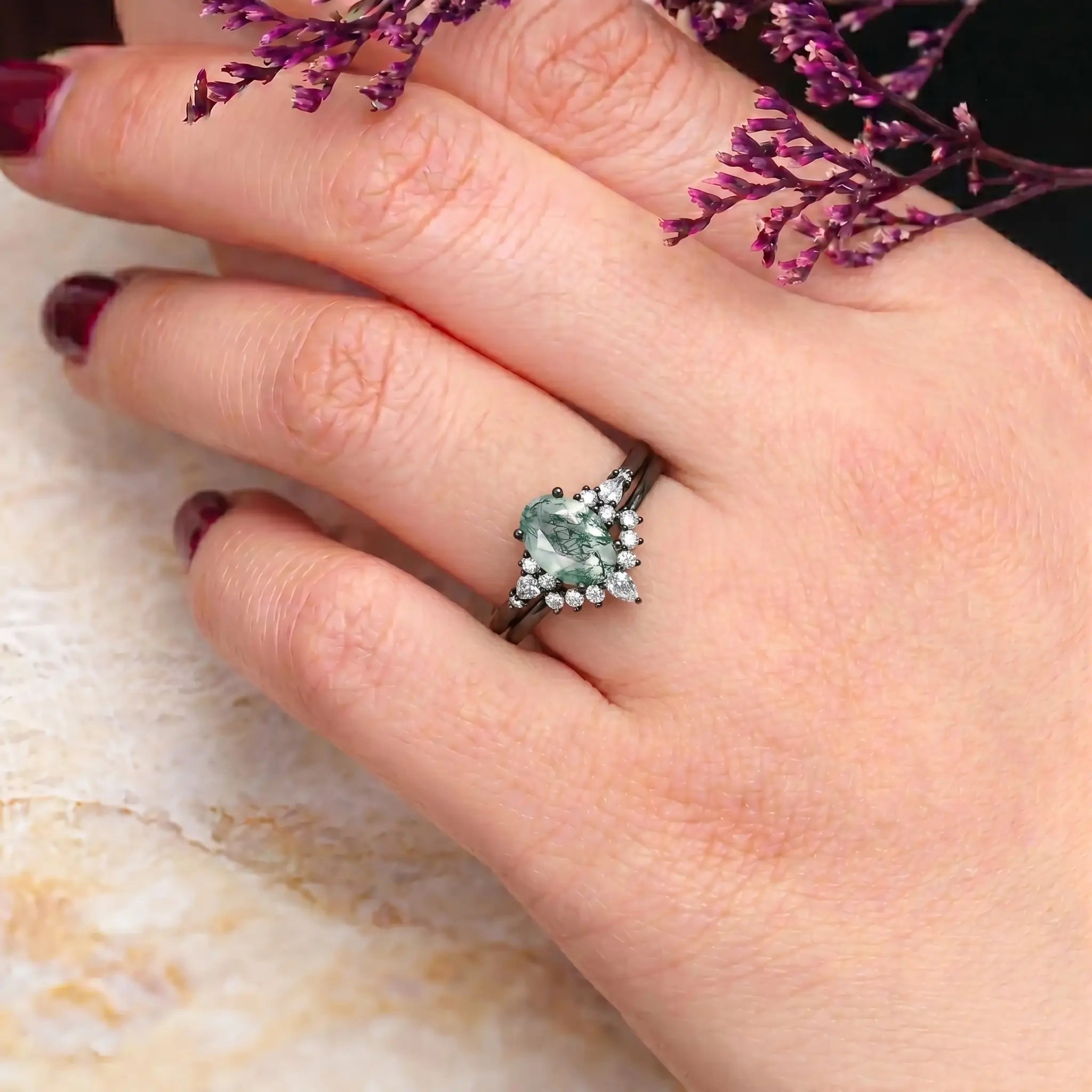 Woman wearing oval moss agate engagement ring set black gold moissanite halo