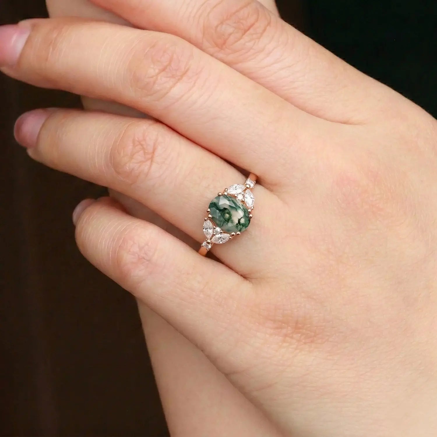 Woman wearing oval moss agate rose gold engagement ring with pear diamond cluster