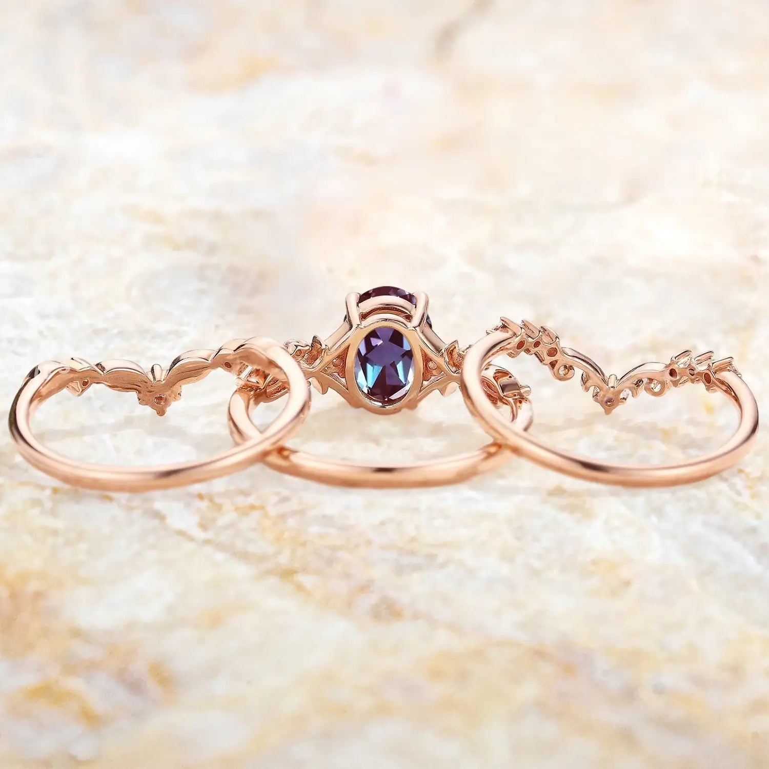 Oval alexandrite engagement ring with two matching wedding bands displayed separately