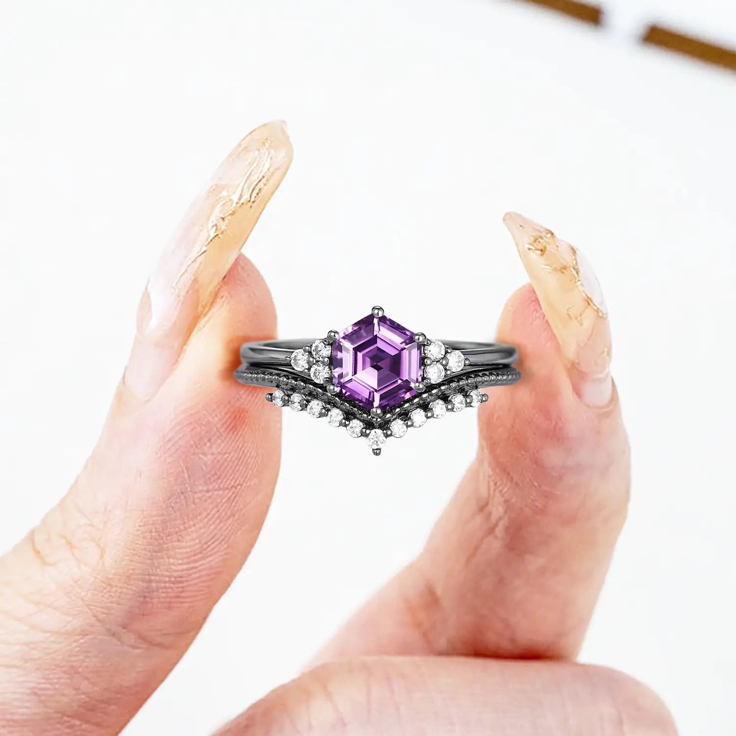 Woman wearing hexagon amethyst engagement ring with moissanite cluster and milgrain chevron wedding band