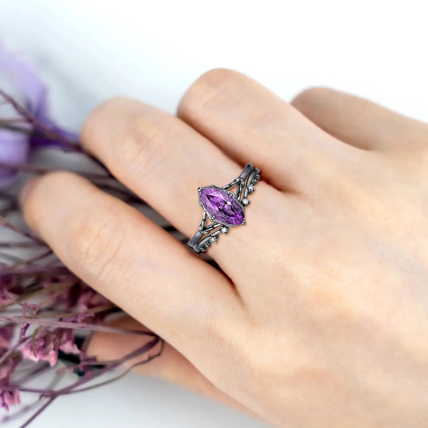 Woman wearing marquise amethyst engagement ring with split shank and curved wedding band in black gold