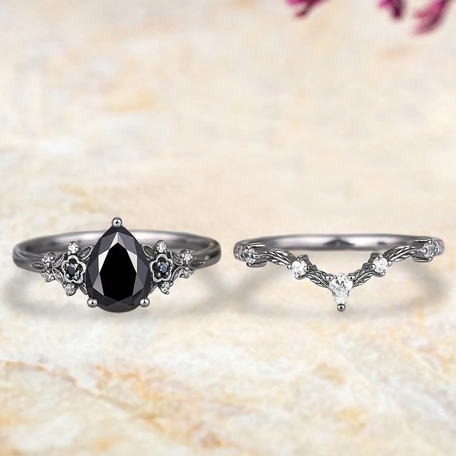 Pear black onyx floral engagement ring and curved leaf wedding band displayed separately showing Gothic nature inspired bridal set