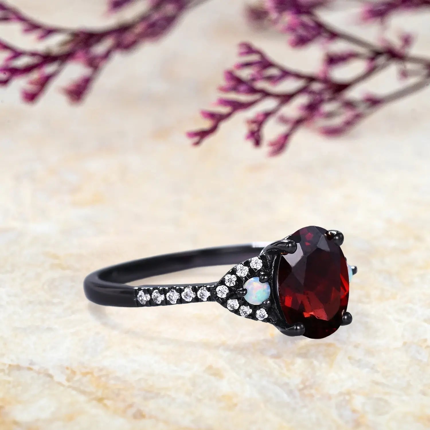 Side view of garnet opal ring showing black gold band and three-stone setting