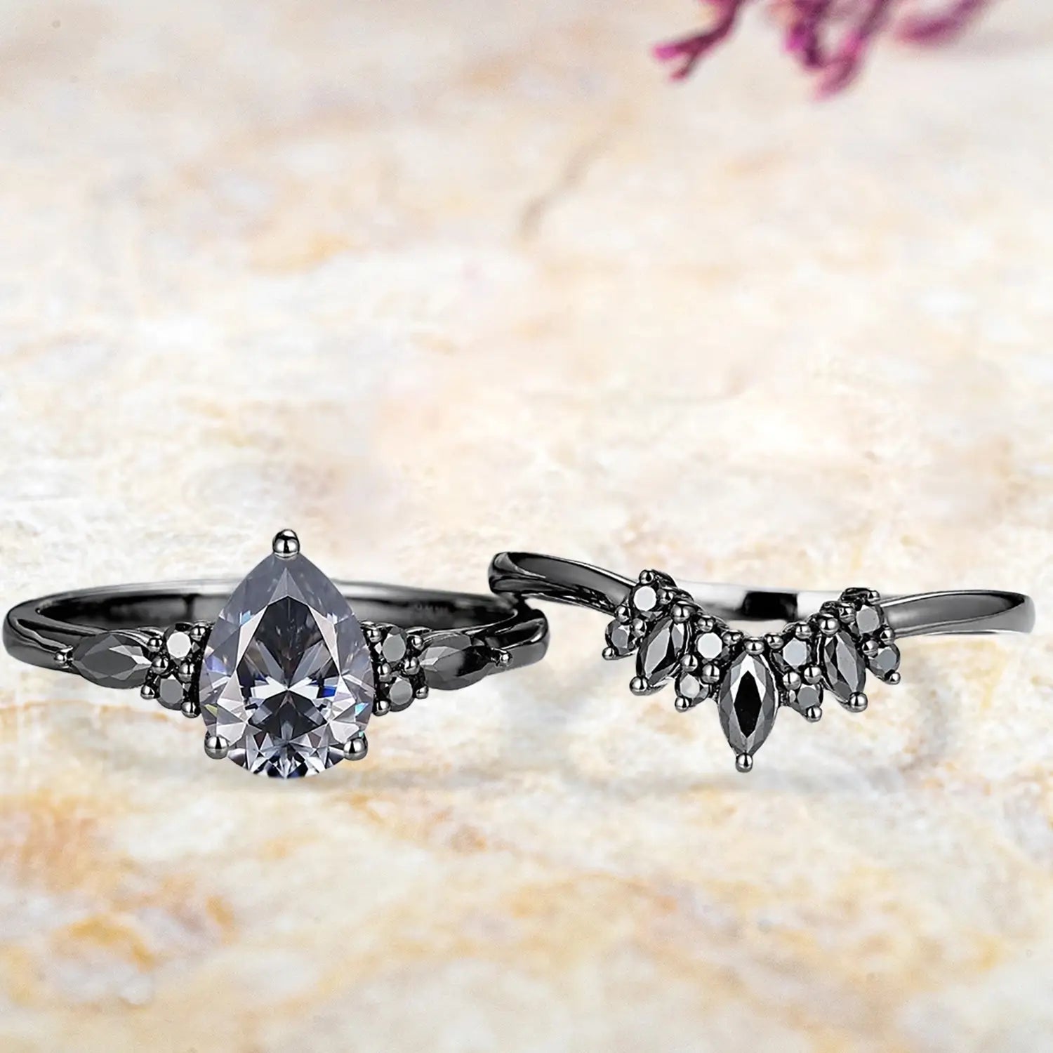 Pear gray moissanite cluster engagement ring and black onyx sunburst wedding band displayed separately showing Gothic bridal set