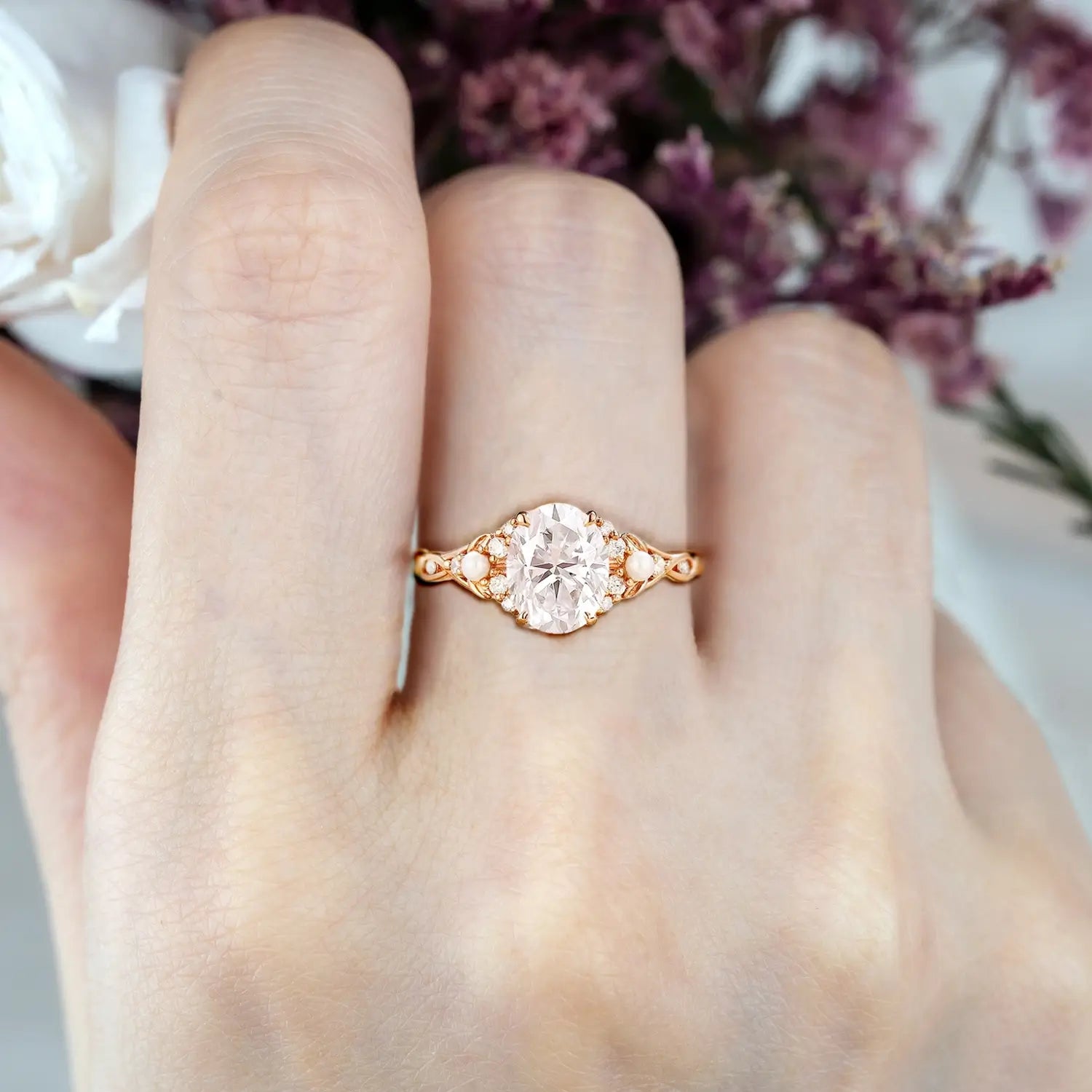 Woman wearing oval moissanite engagement ring with pearl cluster and twisted rose gold band