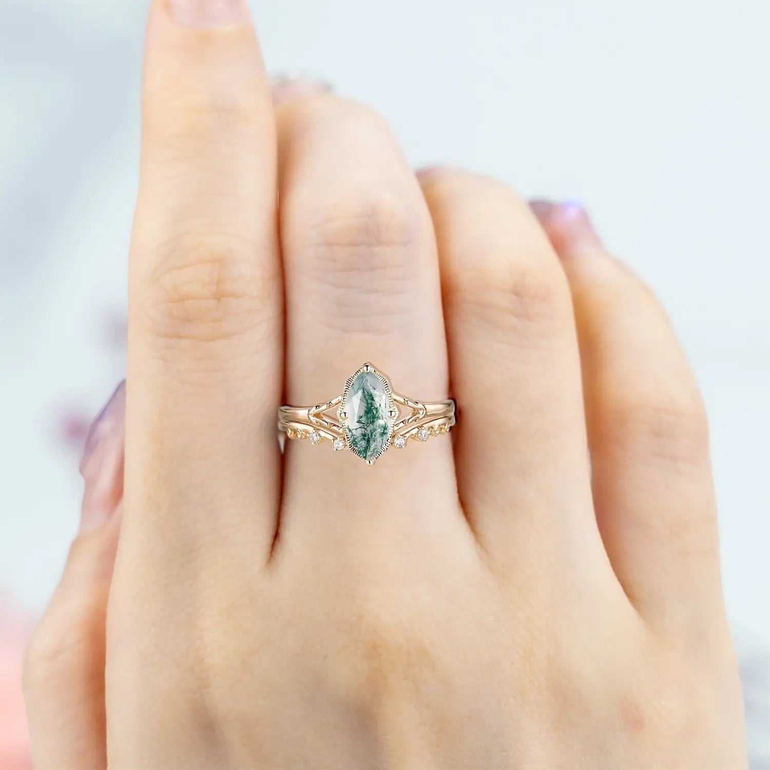 Woman wearing marquise moss agate engagement ring with split shank and open curved moissanite wedding band