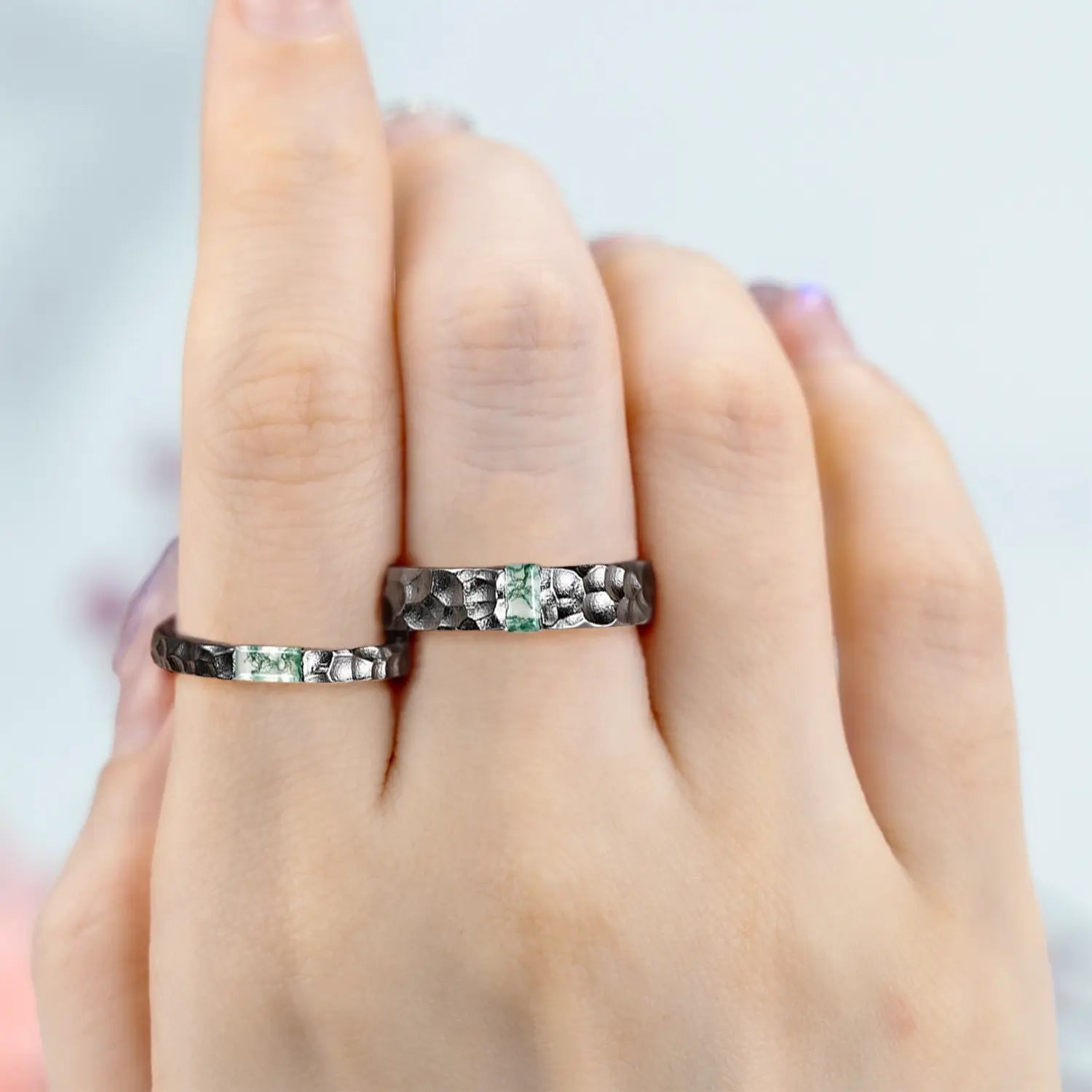 Couple wearing matching moss agate wedding bands in hammered black gold his and hers rings