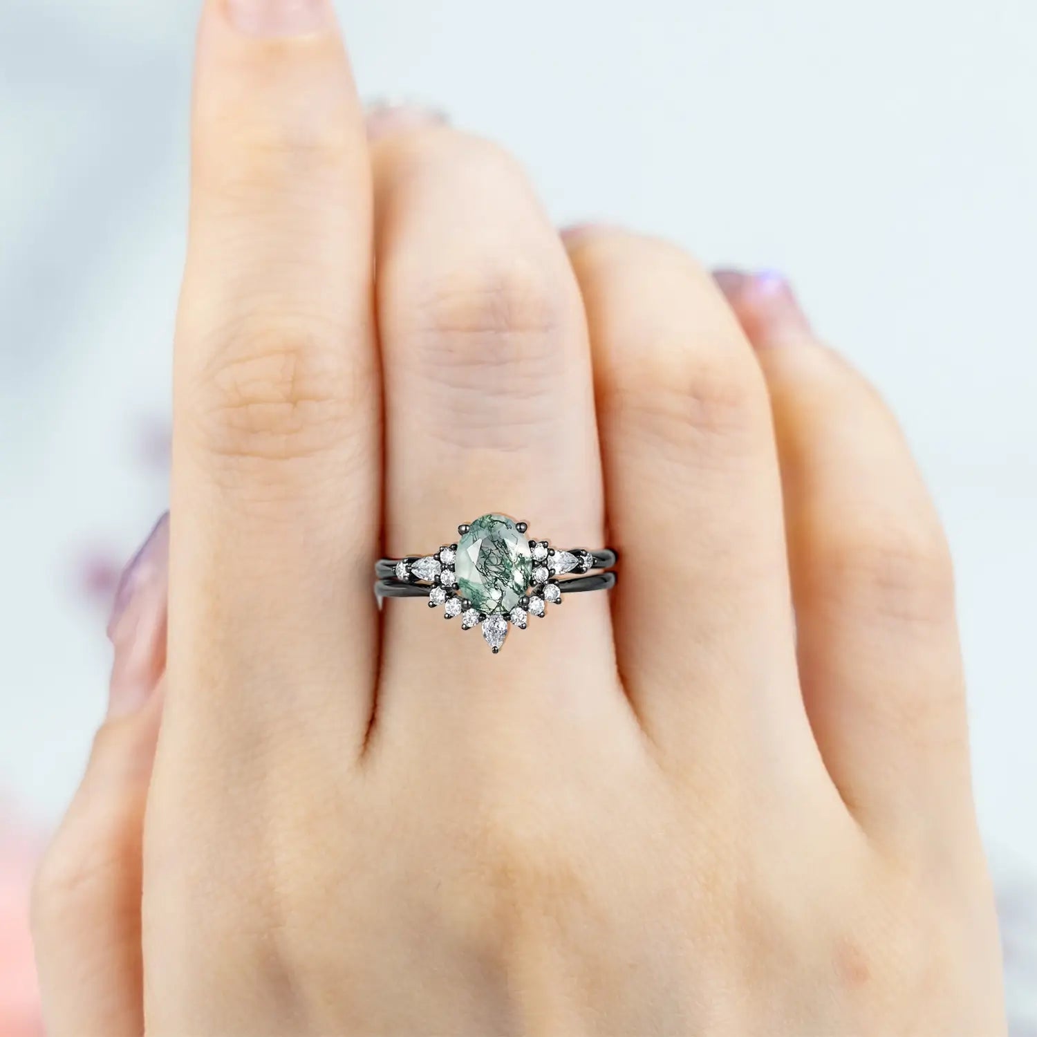 Woman wearing oval moss agate engagement ring set black gold moissanite halo