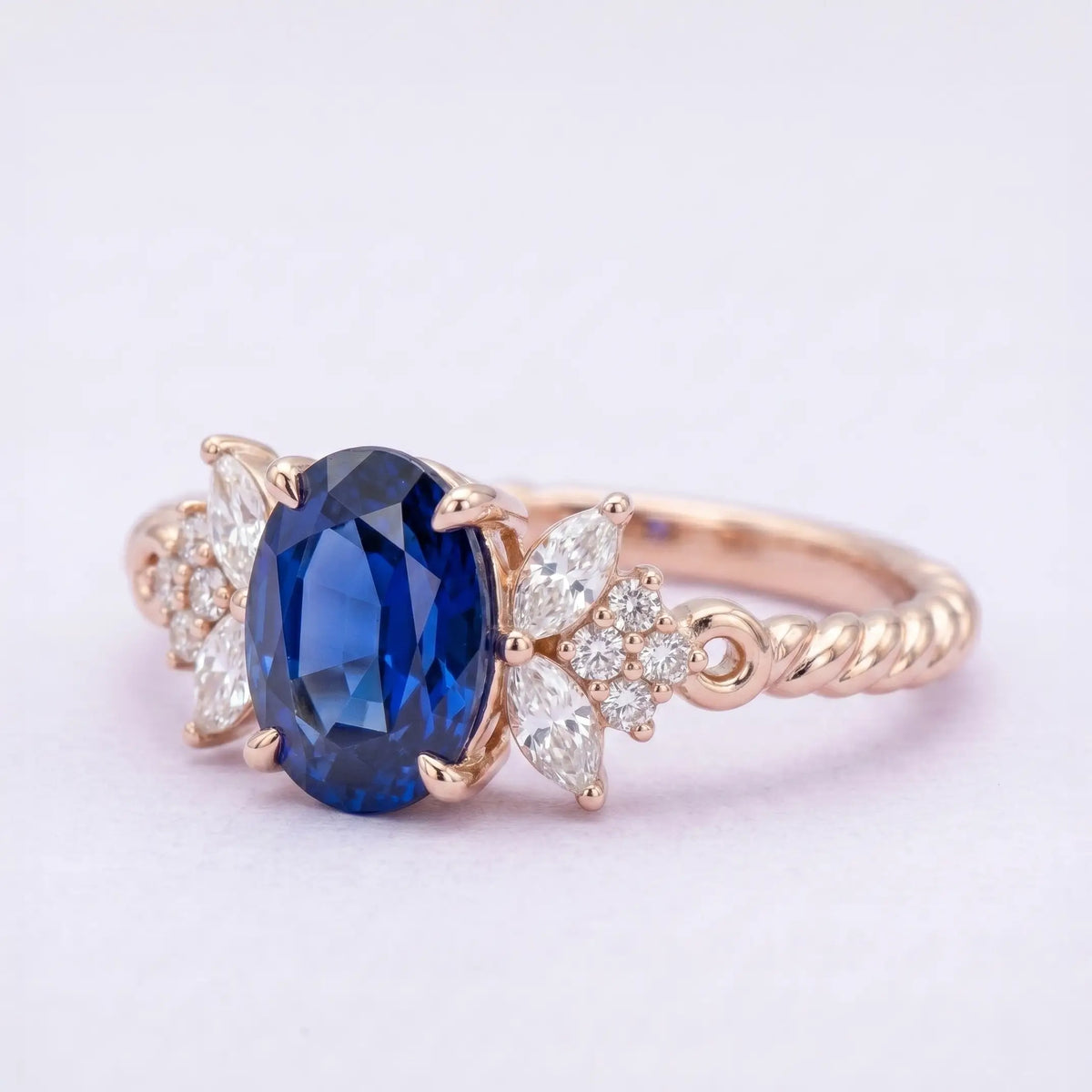 Artisanal gold cluster ring featuring oval blue sapphire and handcrafted twisted rope band detail