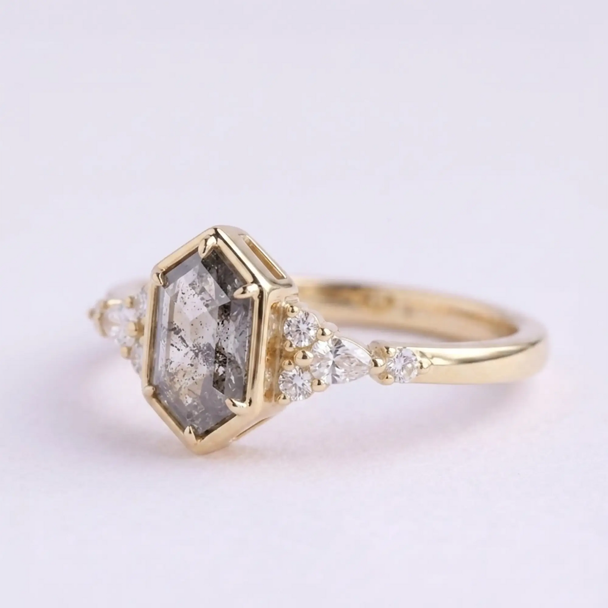 Artisanal gold ring featuring hexagon cut salt and pepper diamond and pear shaped side stones