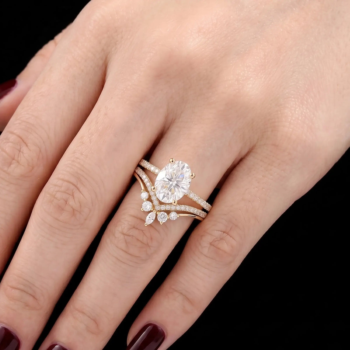 Oval moissanite engagement ring set worn on hand with a matching V-shaped wedding band