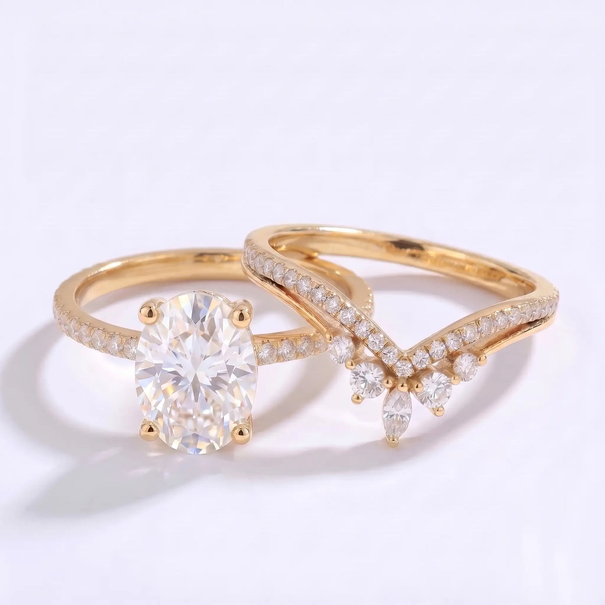 Oval moissanite engagement ring and matching V-shaped wedding band displayed separately