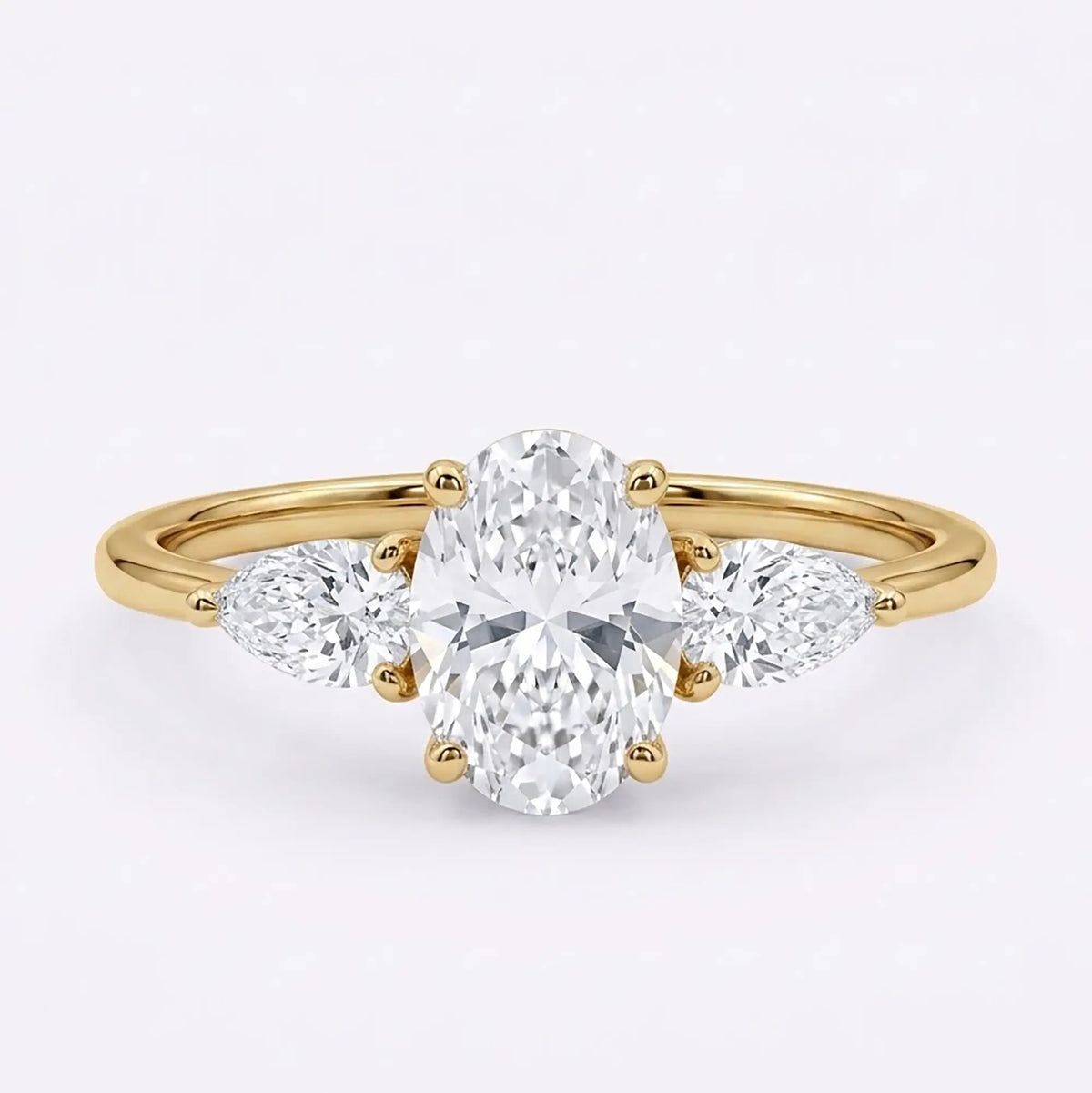 Classic oval moissanite three stone engagement ring with pear side stones in yellow gold