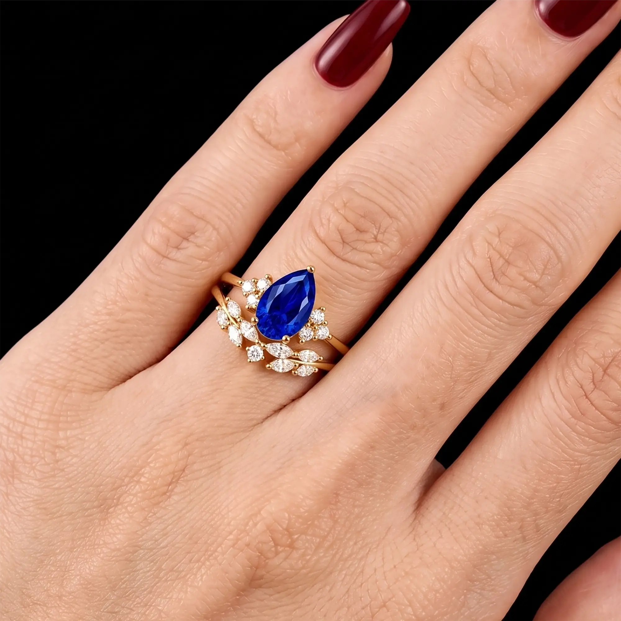 Pear cut sapphire cluster bridal ring set worn on hand with matching wedding band