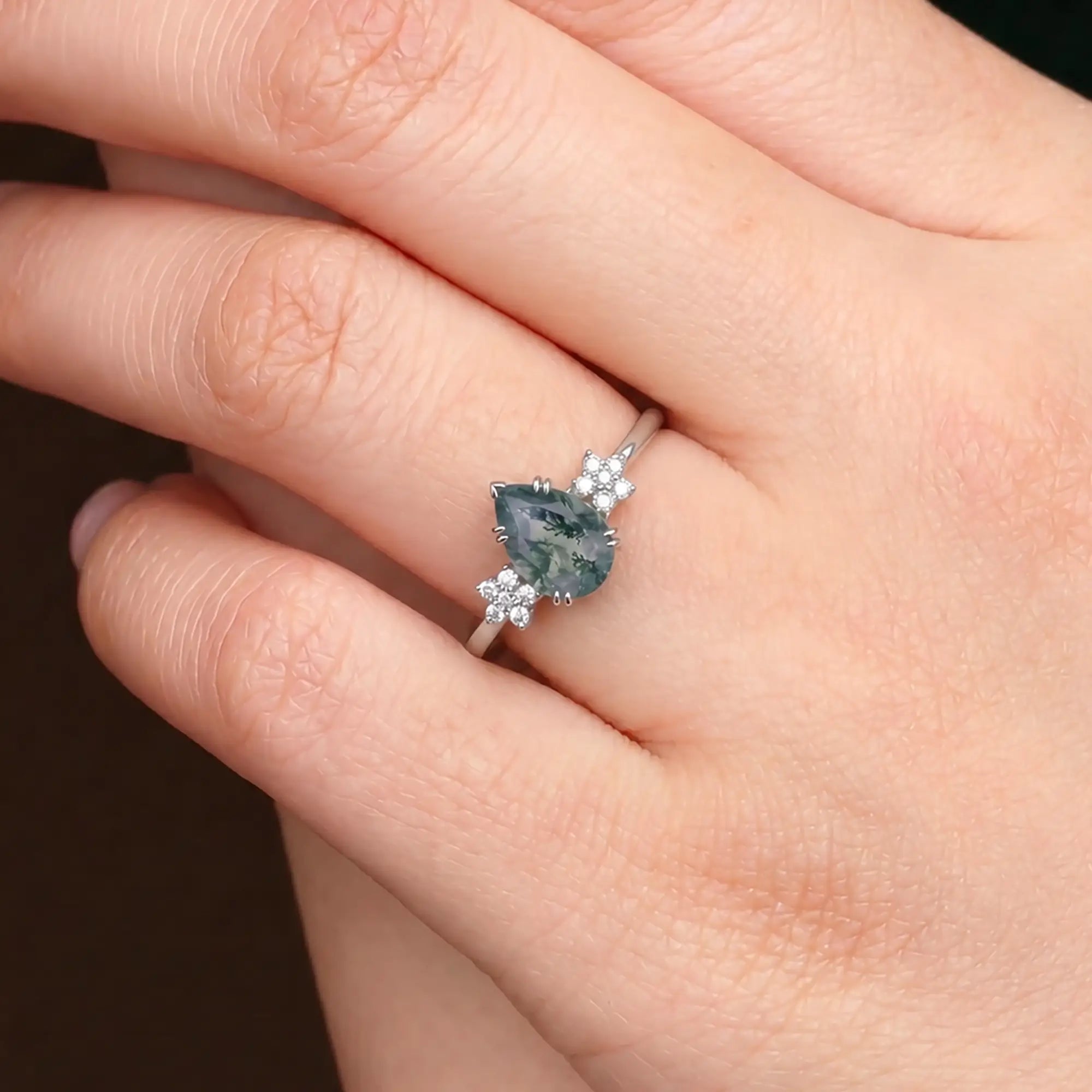 Luminous handmade botanical pear moss agate ring on hand showing intricate 10-moissanite wildflower cluster