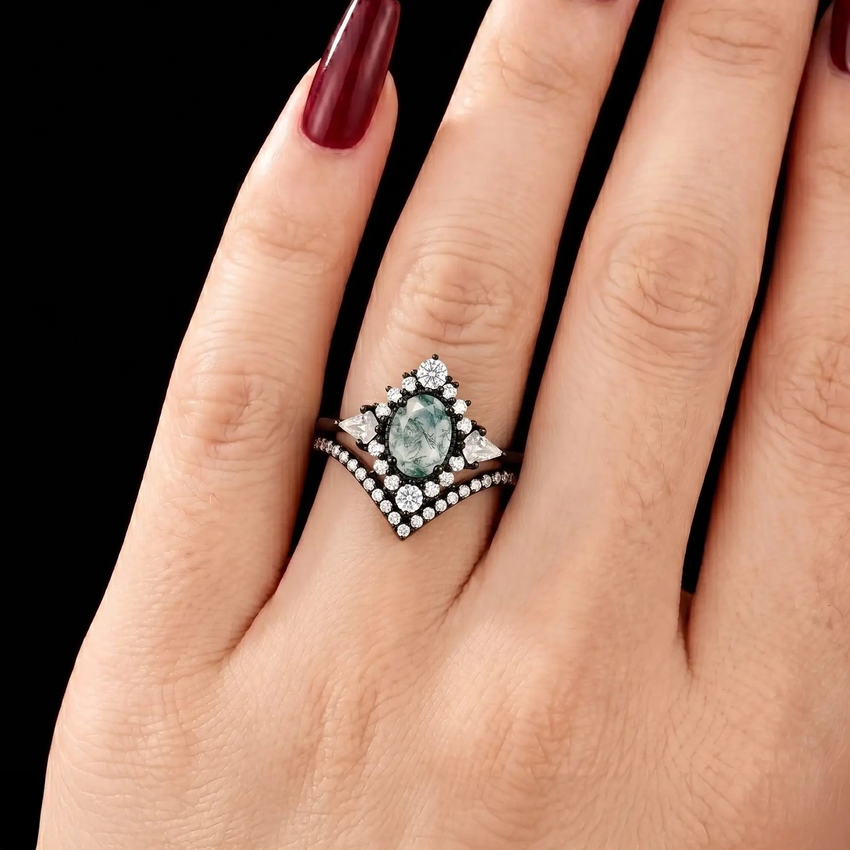 Luxurious dark romantic natural oval moss agate kite halo stacking bridal ring set shown on a woman's finger