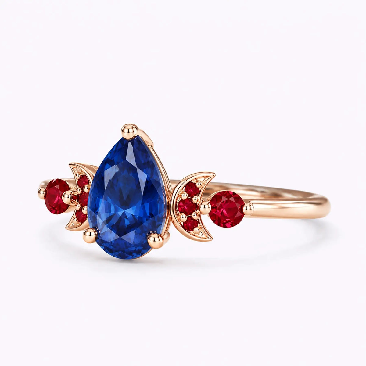 Left view of pear sapphire ring with ruby side stones and crescent moon details