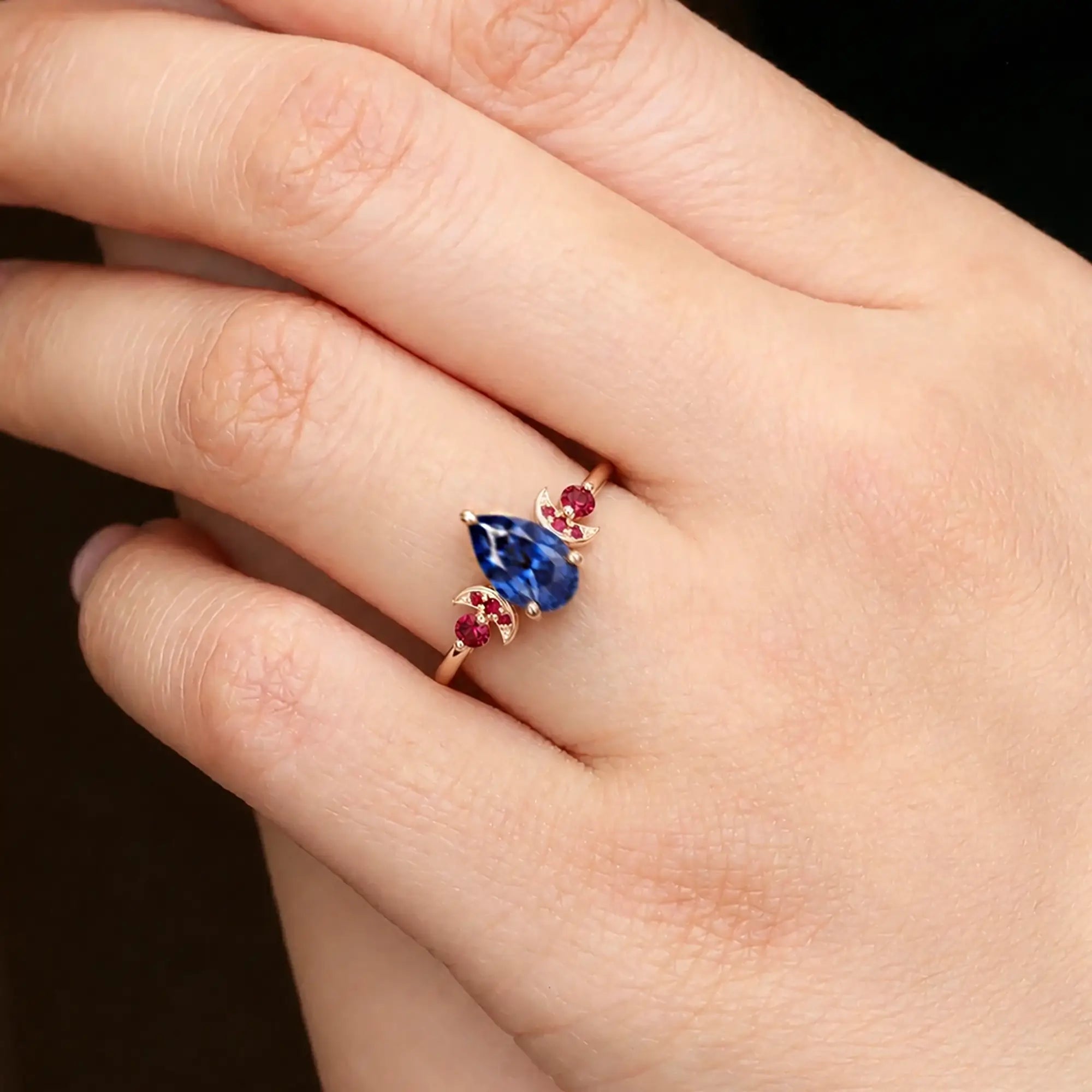 Pear cut sapphire ring worn on hand with crescent moon design details