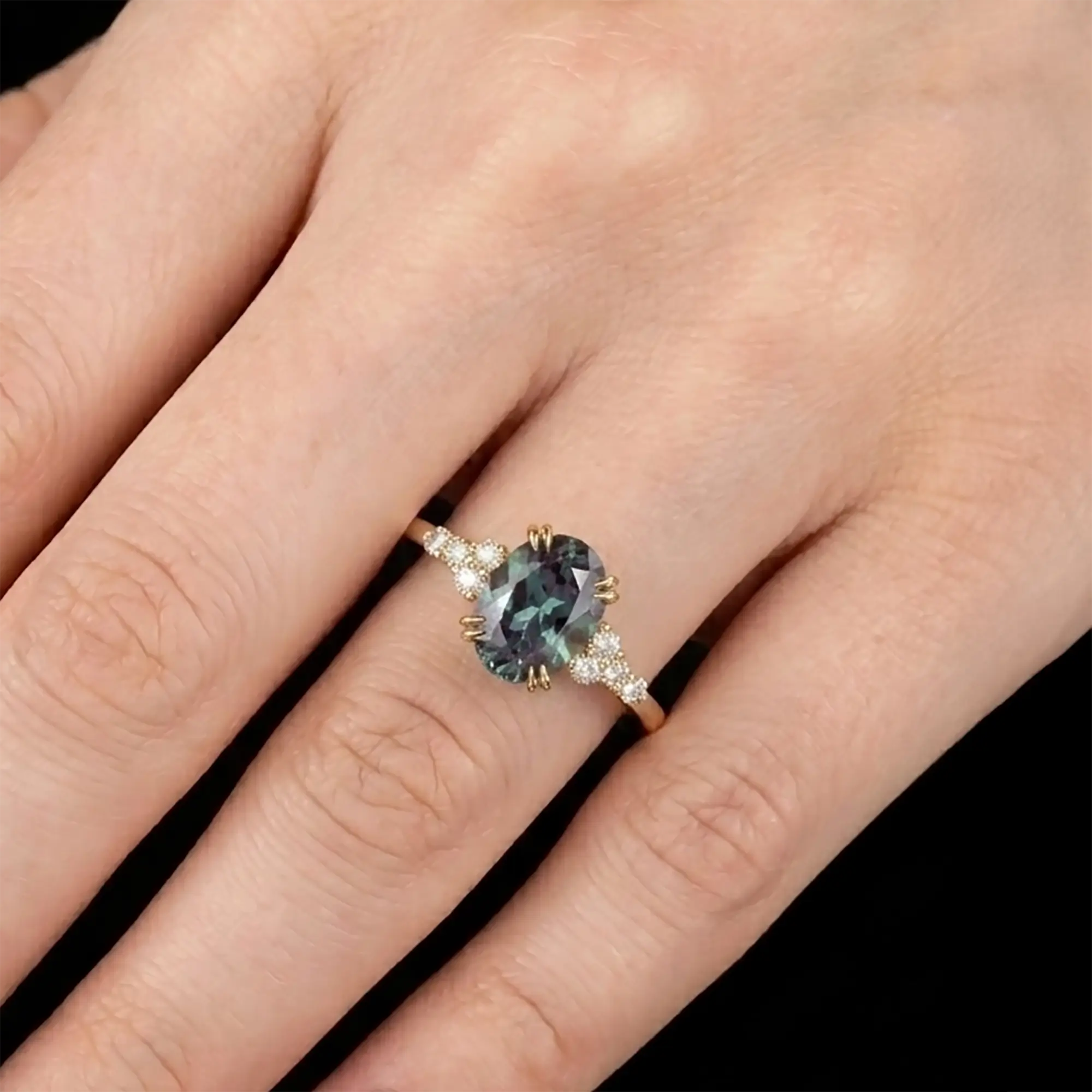Dainty alternative bridal oval alexandrite cluster anniversary ring shown worn on a woman finger