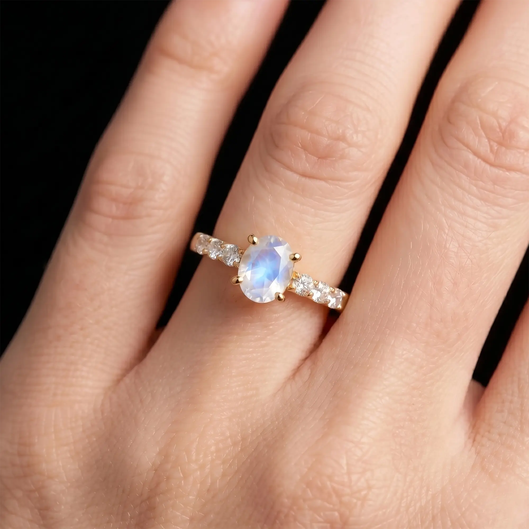 Luminous handmade oval moonstone ring on hand showing ethereal blue adularescence flash