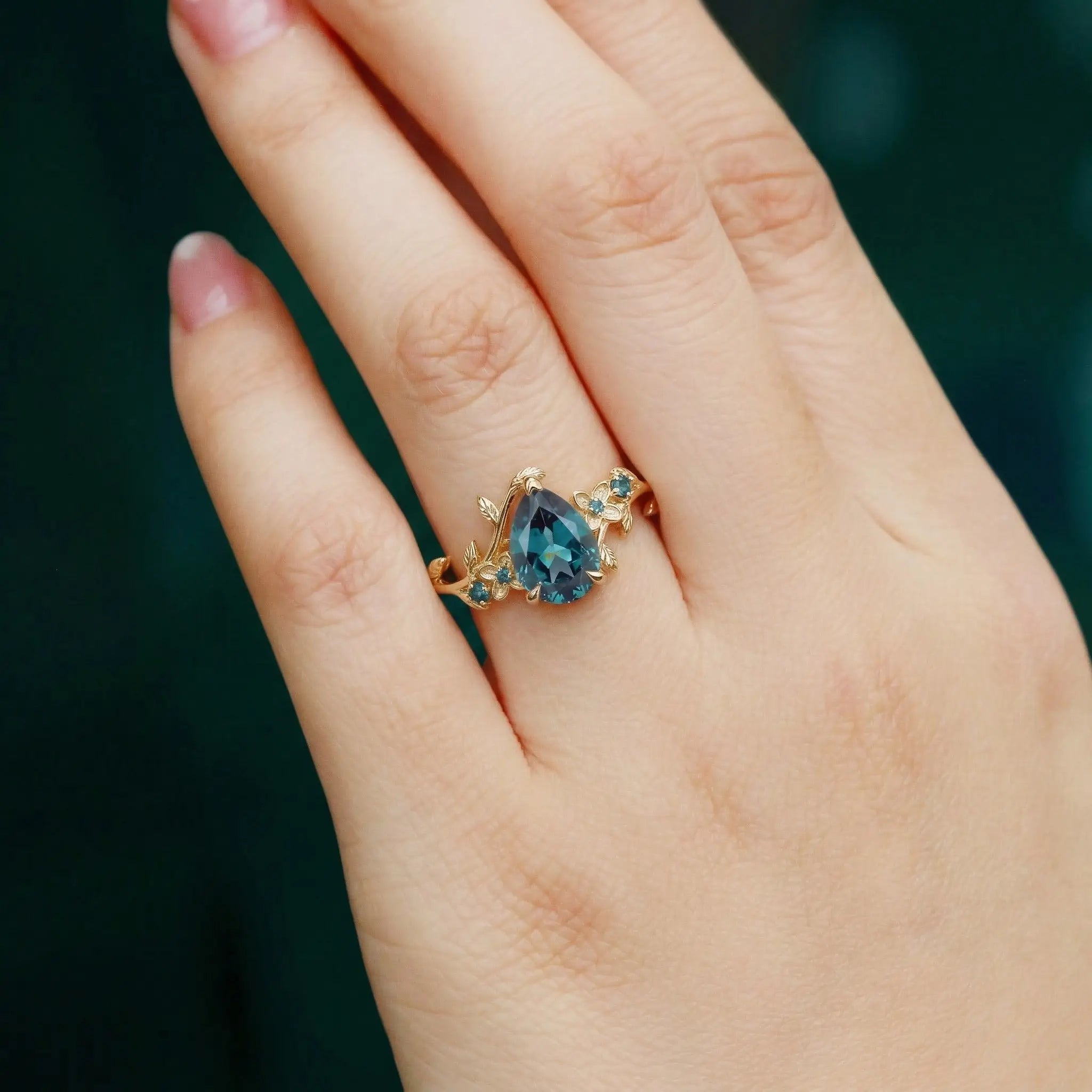 Woman wearing pear cut alexandrite floral engagement ring yellow gold jewelry orleone