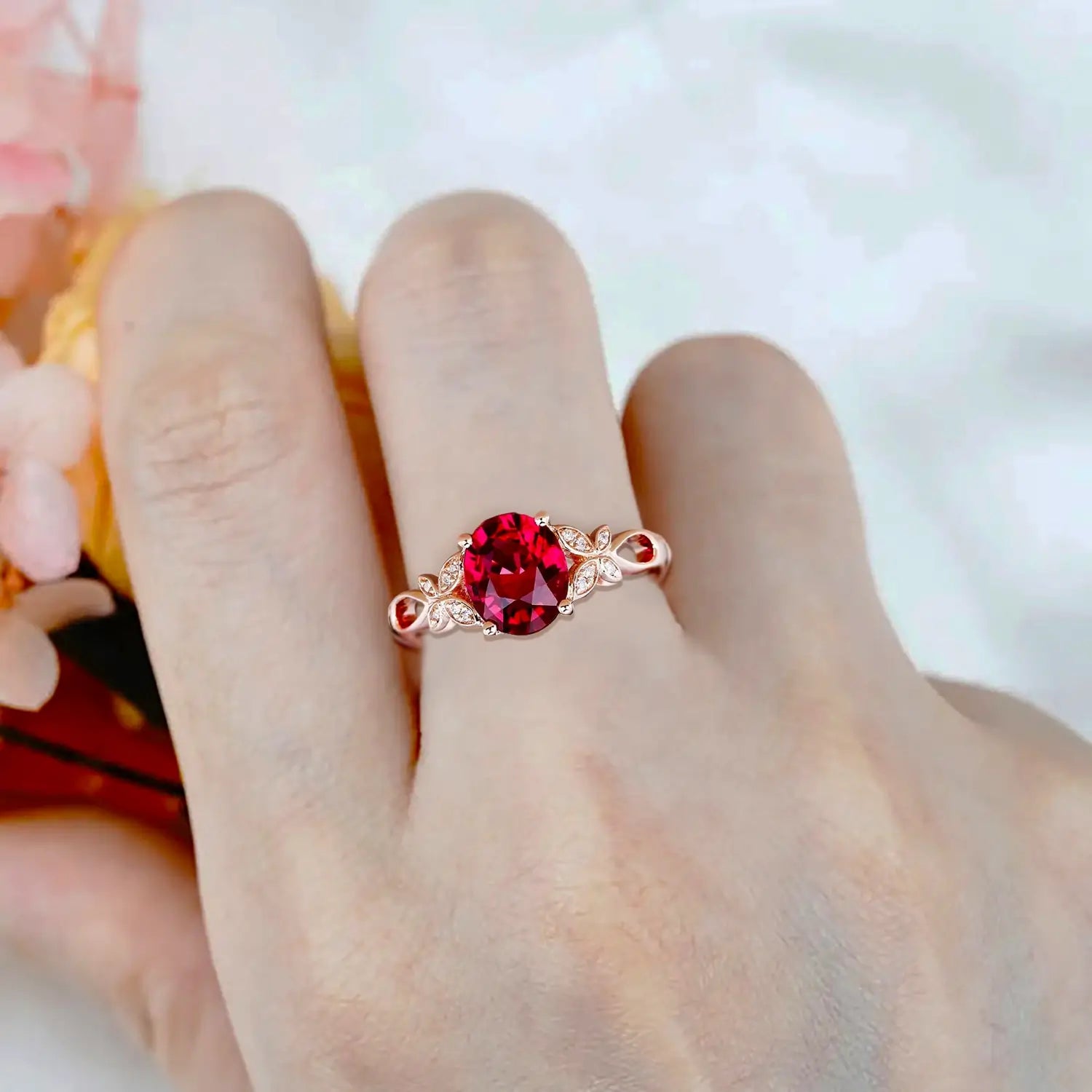 Woman wearing oval ruby engagement ring with butterfly floral band in rose gold showing elegant style