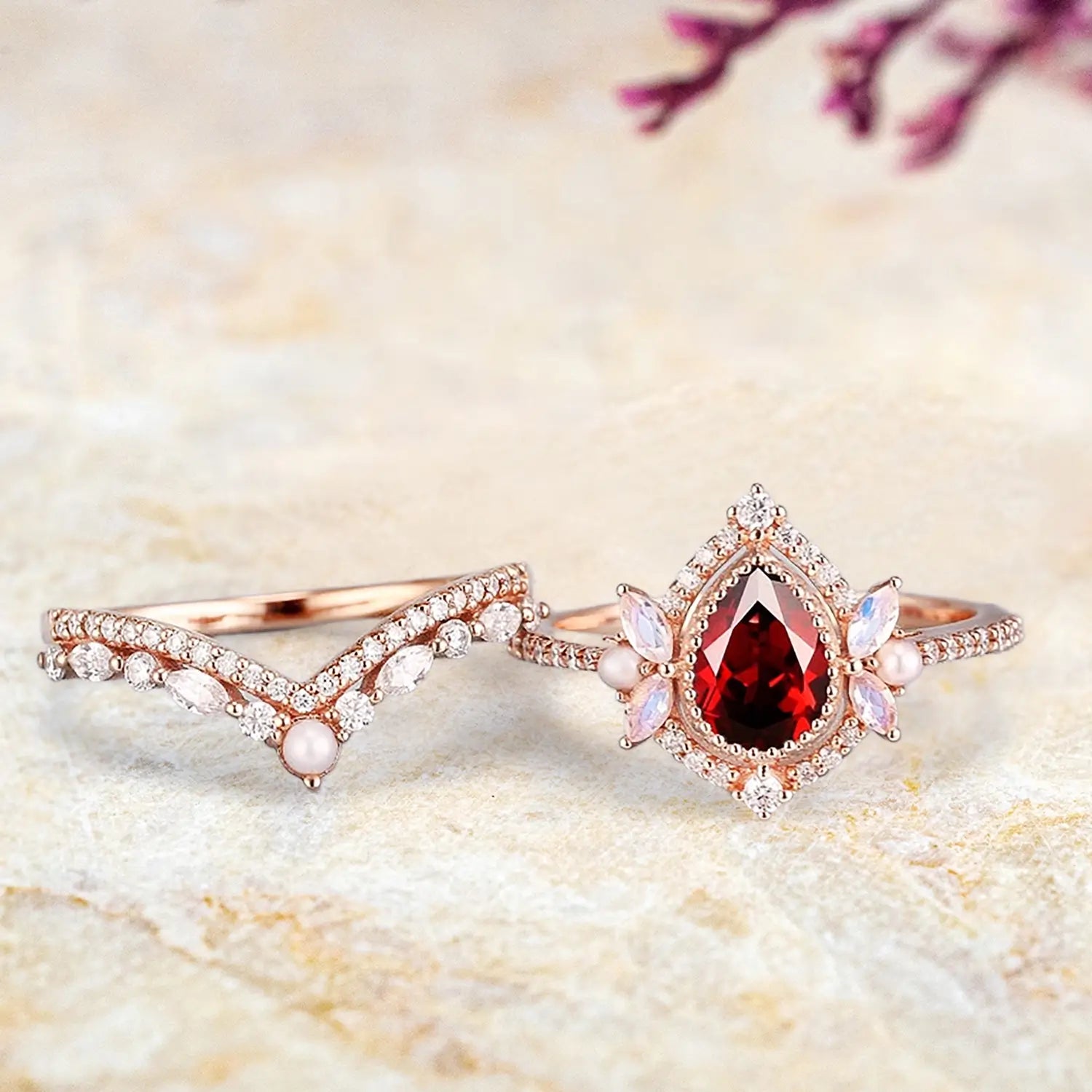 Pear ruby pearl moonstone engagement ring and curved wedding band displayed separately showing unique bridal set