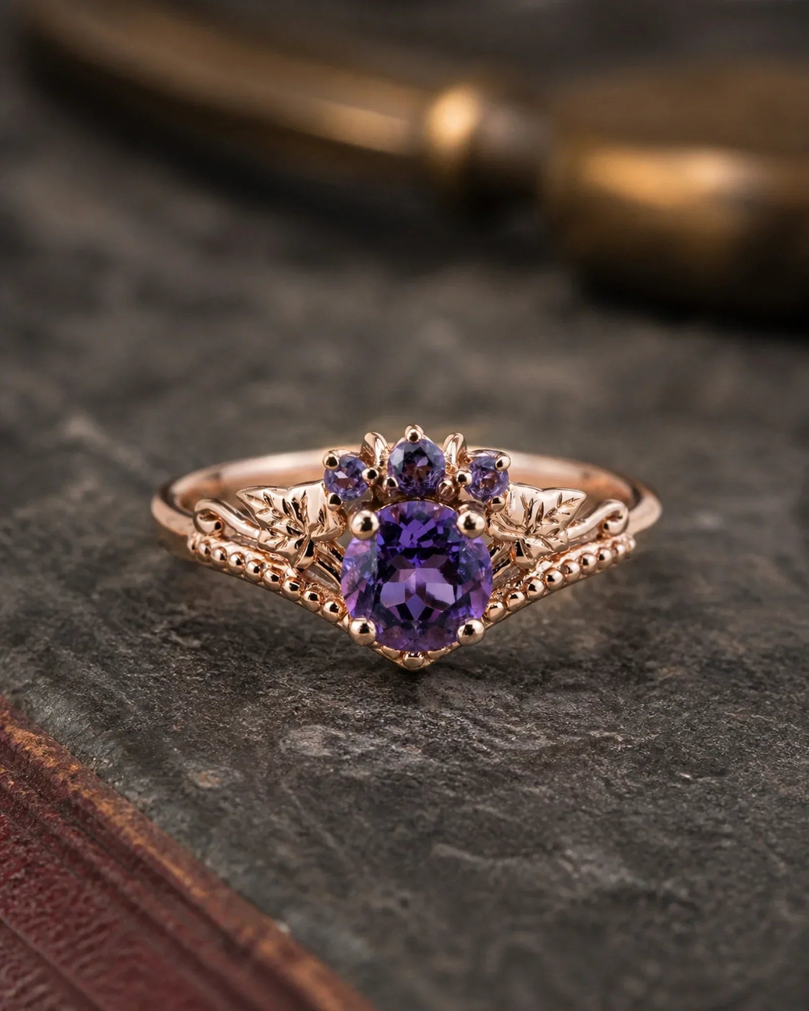 Rose gold amethyst botanical engagement ring photographed on dark vintage limestone and aged leather