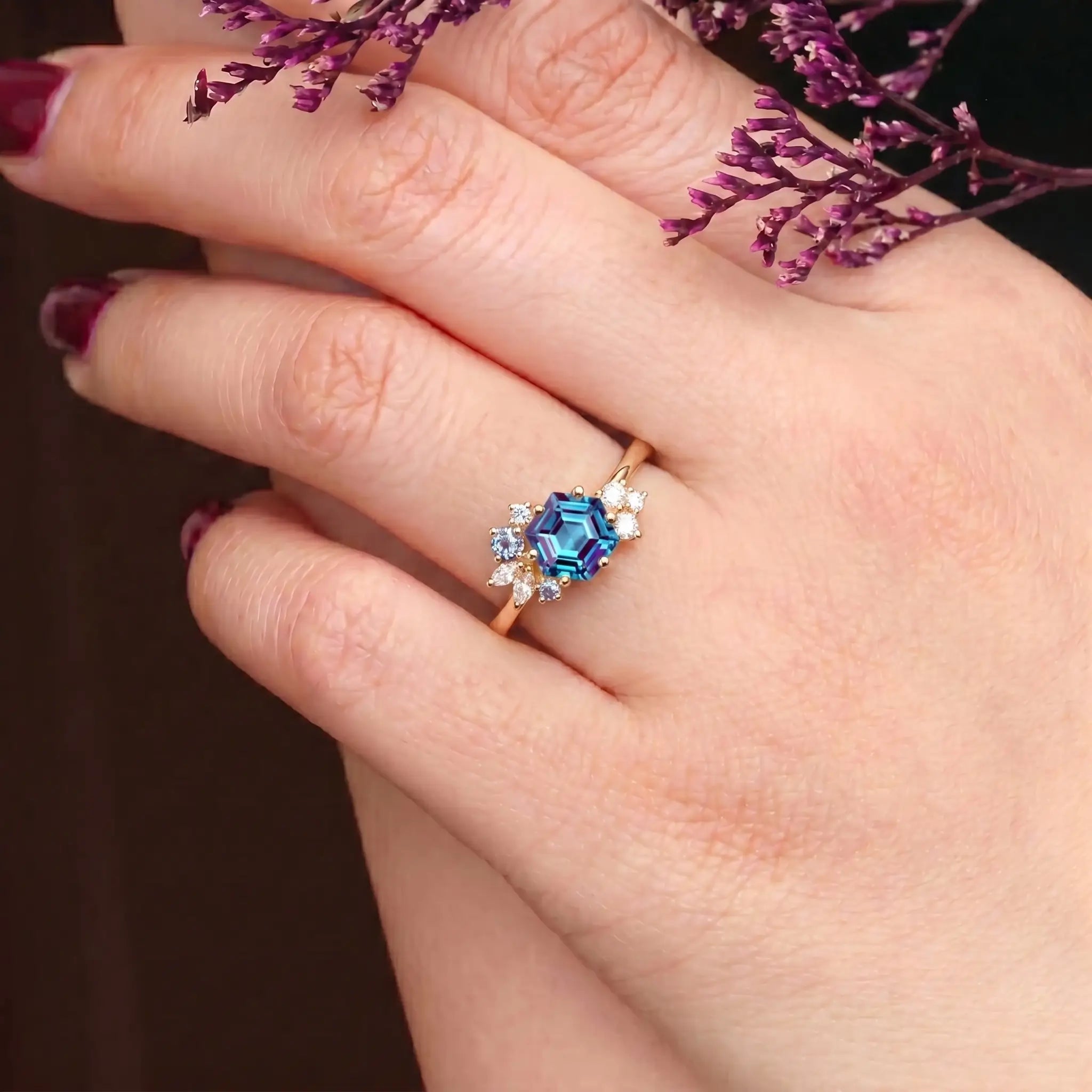 Woman wearing hexagon alexandrite yellow gold engagement ring cluster design