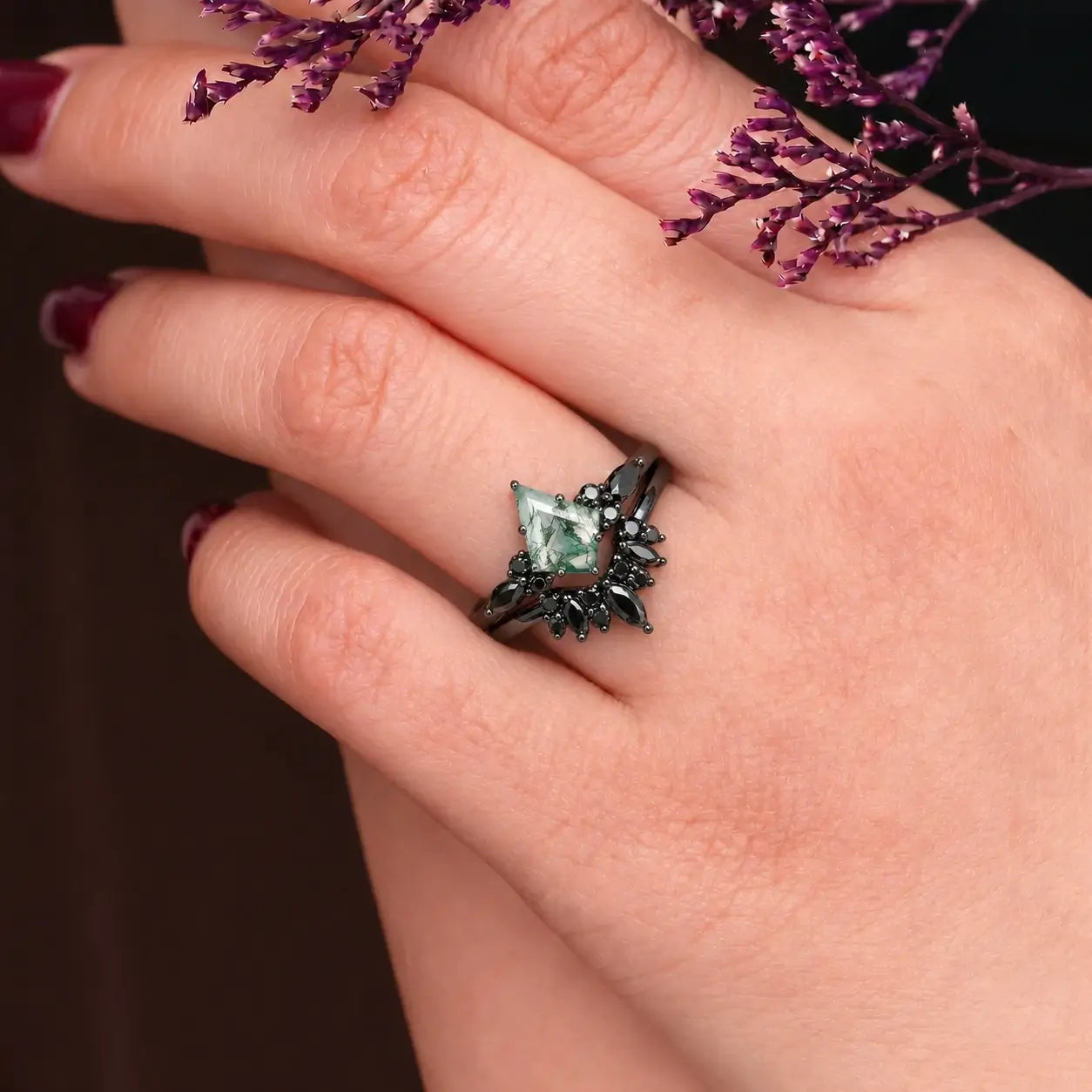 Woman wearing kite moss agate engagement ring with black moissanite cluster and chevron wedding band
