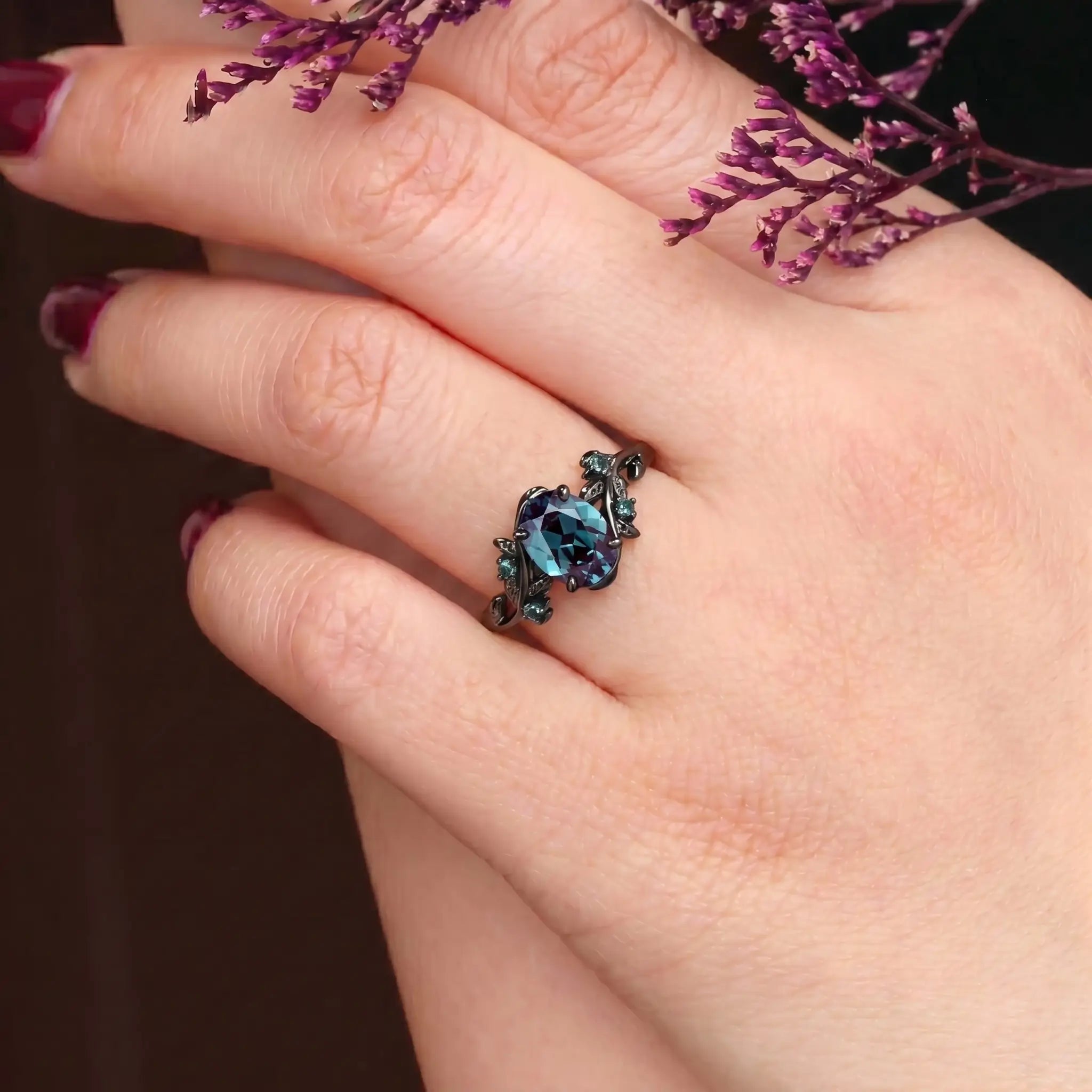 Woman wearing oval alexandrite engagement ring with nature twig branch band showing color change in black gold