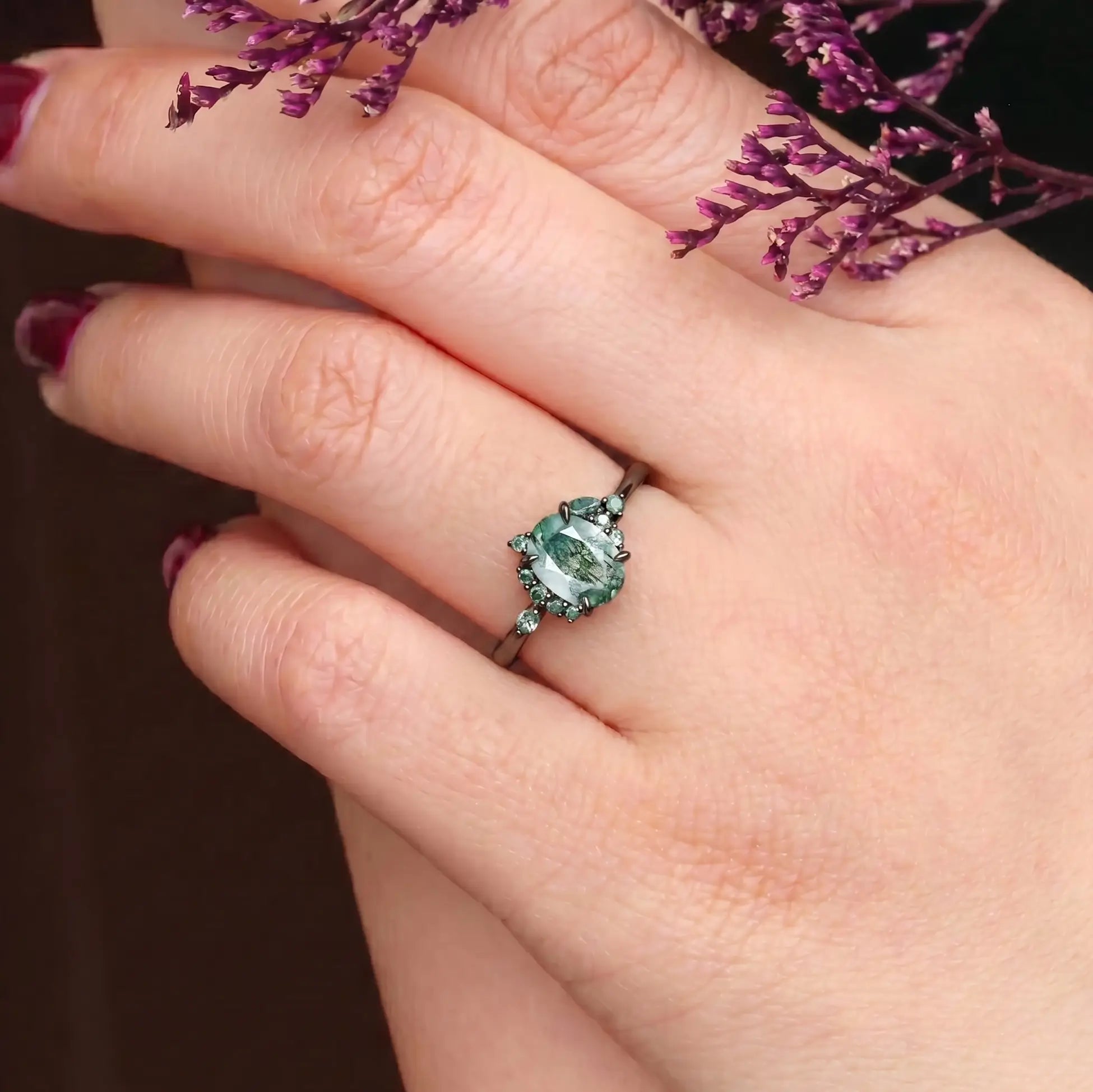 Woman wearing oval moss agate Gothic engagement ring black gold claw setting