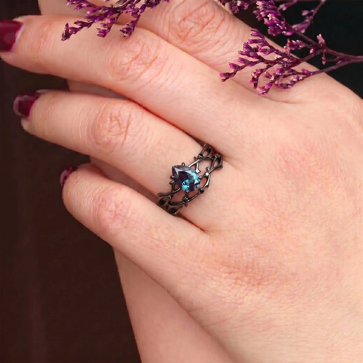 The slender hand of an elegant lady, adorned with a custom Orleone ring—an 18K Black Gold and Lab Alexandrite Twig Branch Ring Set.