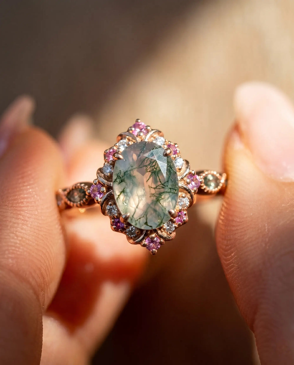 A high-end, custom-made vintage-style halo engagement ring featuring an oval-cut moss agate set in 14K rose gold.