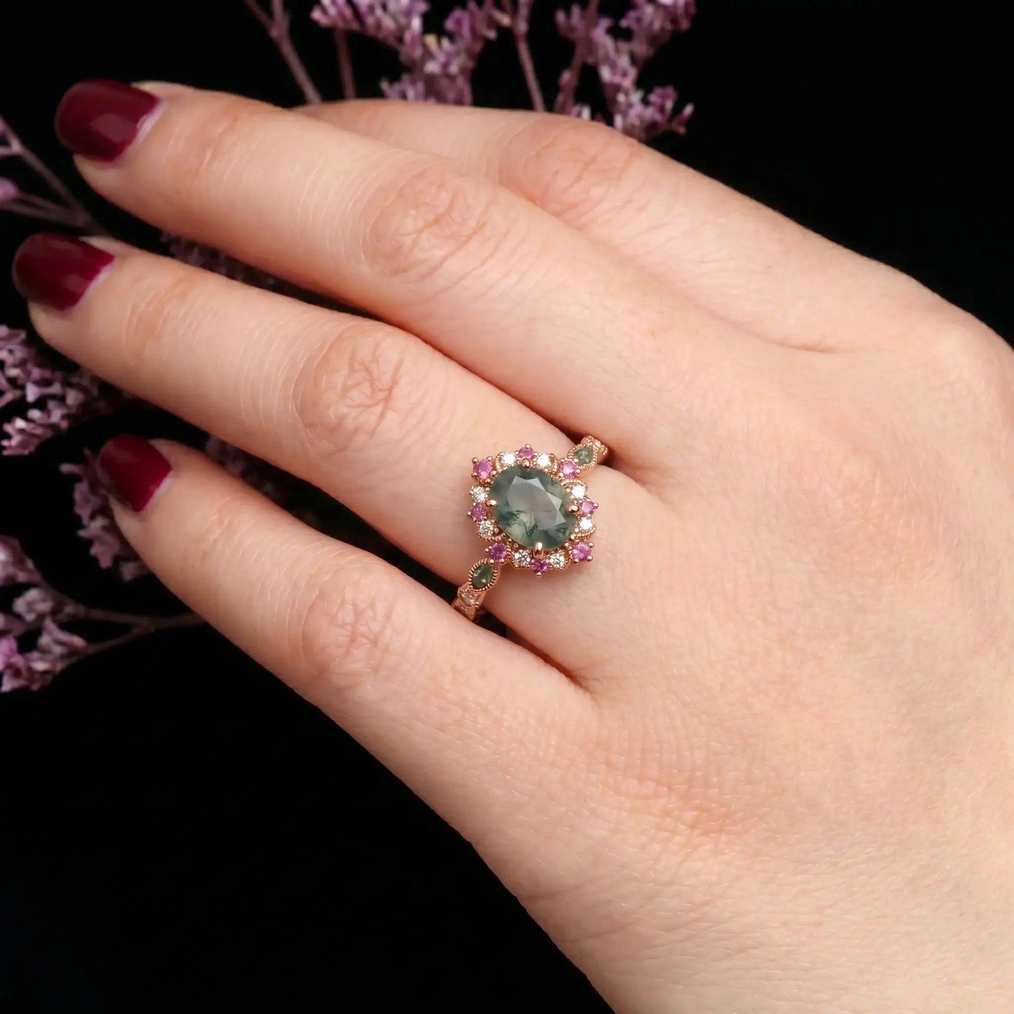 A close-up of a model's hand, wearing a vintage halo moss agate engagement ring with an oval cut from the high-end brand Orleone.