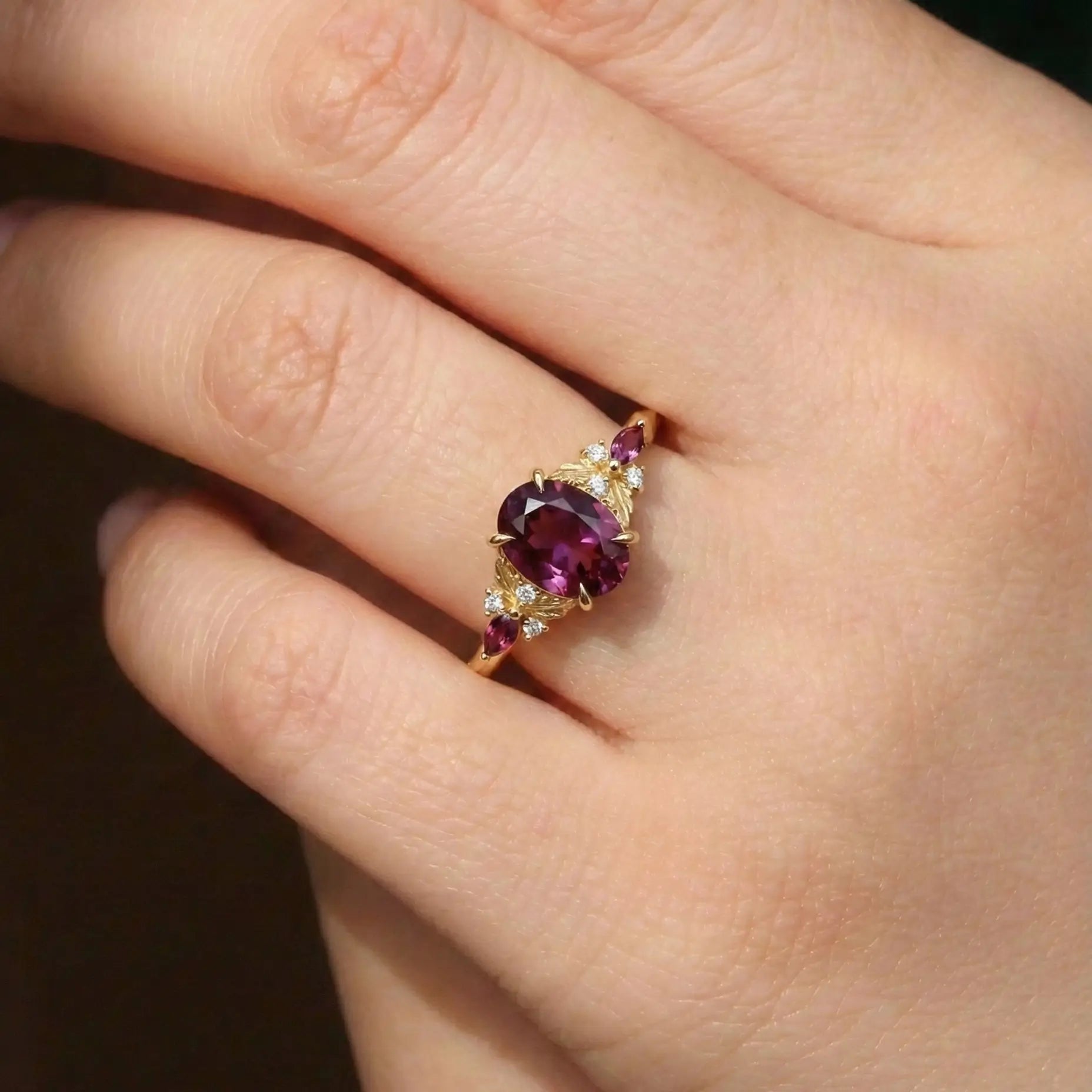 Woman wearing oval alexandrite engagement ring with gold leaf design