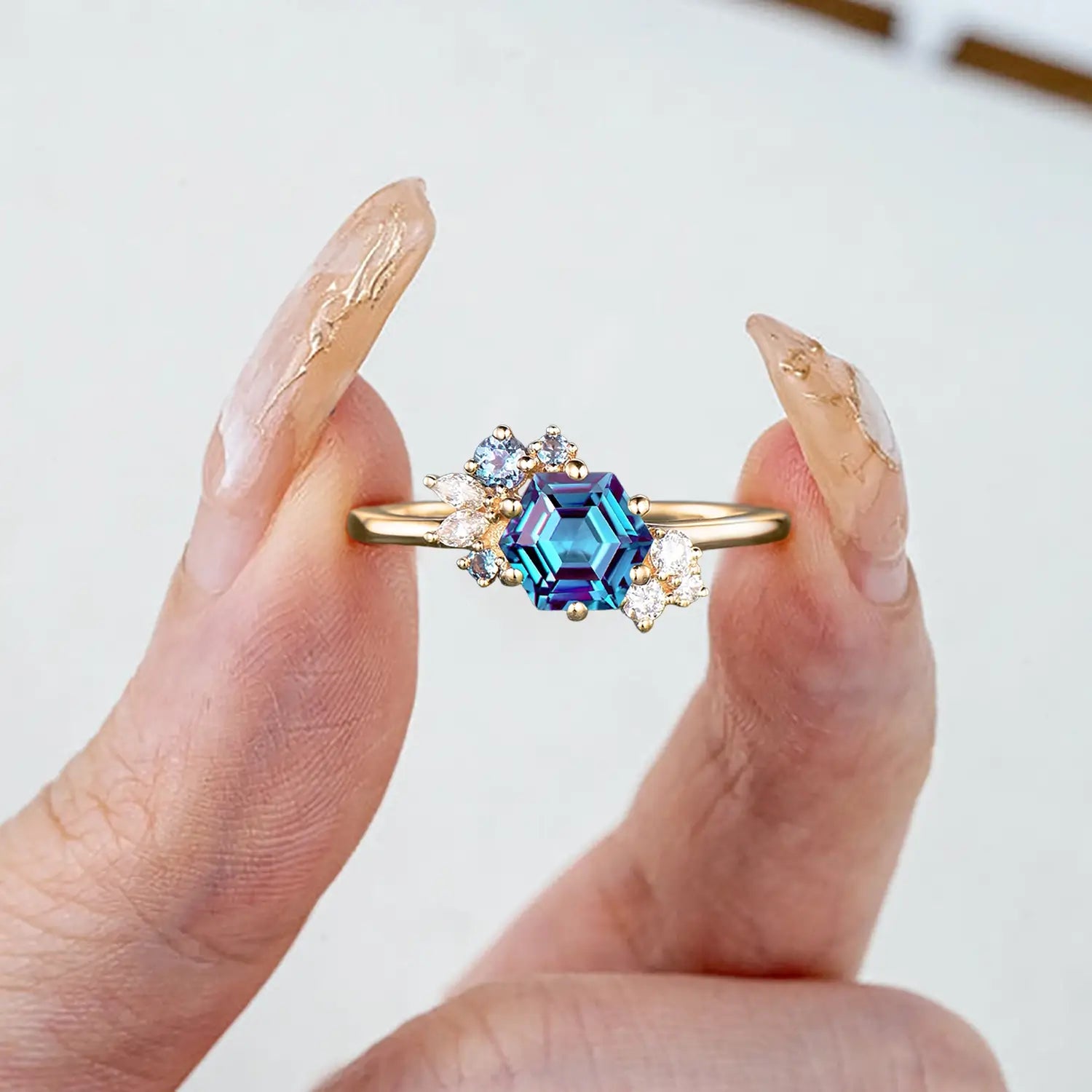 Woman wearing hexagon alexandrite yellow gold engagement ring cluster design