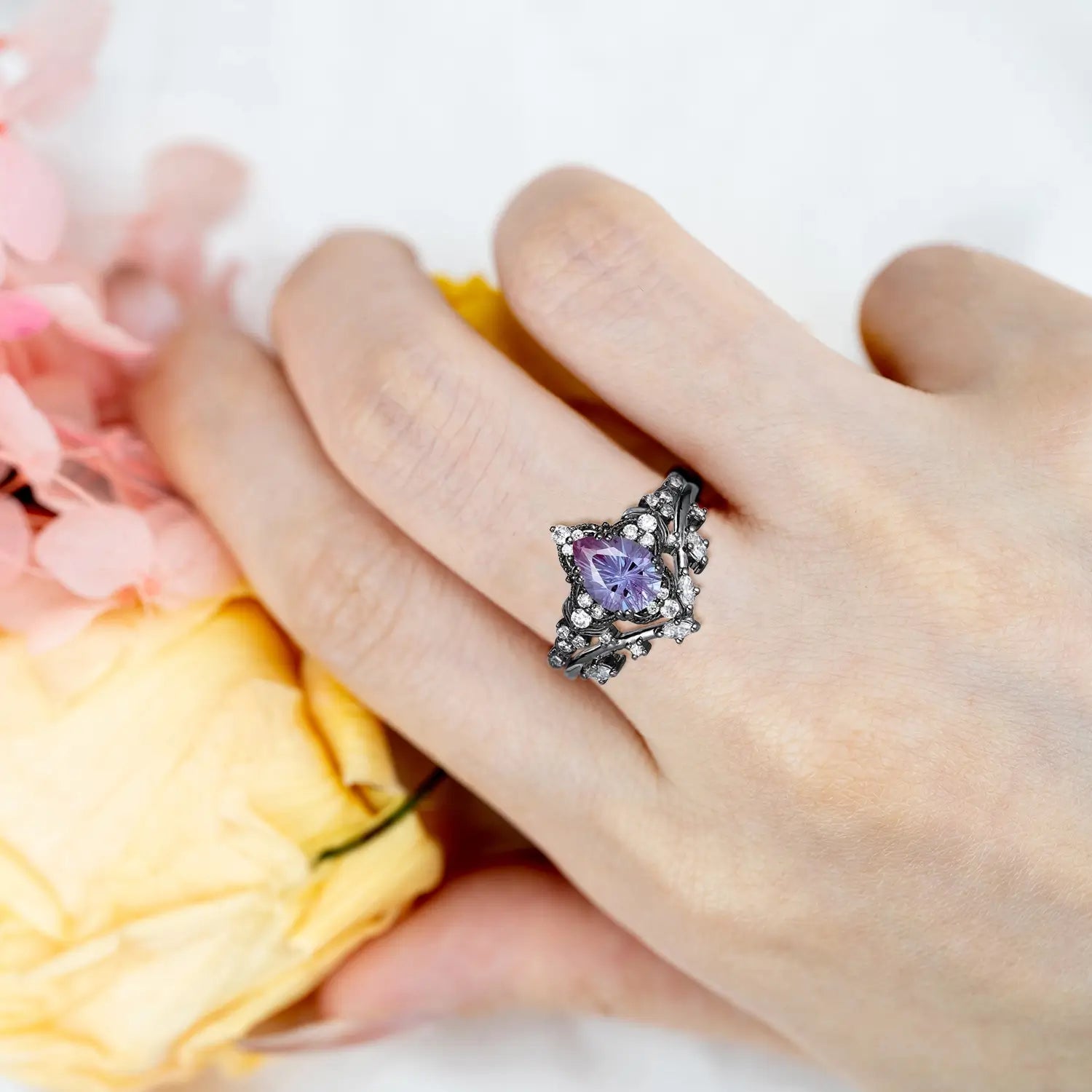 Woman wearing pear alexandrite fireworks engagement ring with leaf cluster and chevron wedding band showing color change