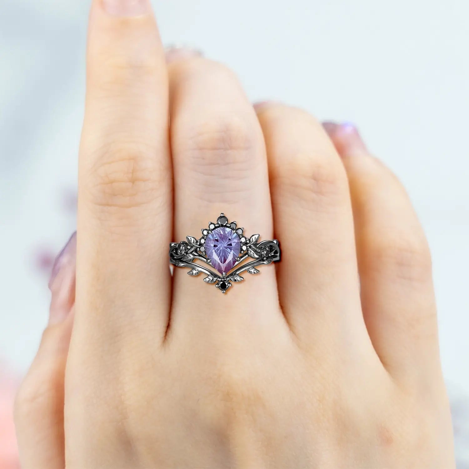 Woman wearing pear alexandrite fireworks engagement ring with leaf halo crown and curved wedding band showing color change