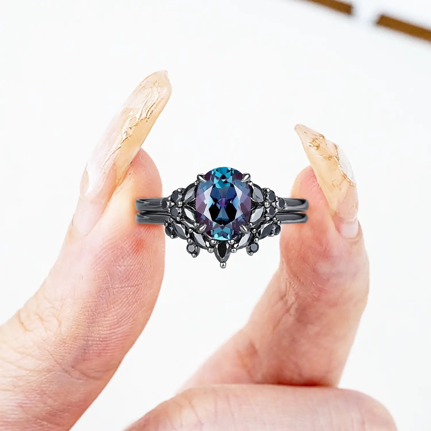 Woman wearing oval alexandrite engagement ring with black onyx cluster and chevron wedding band in black gold