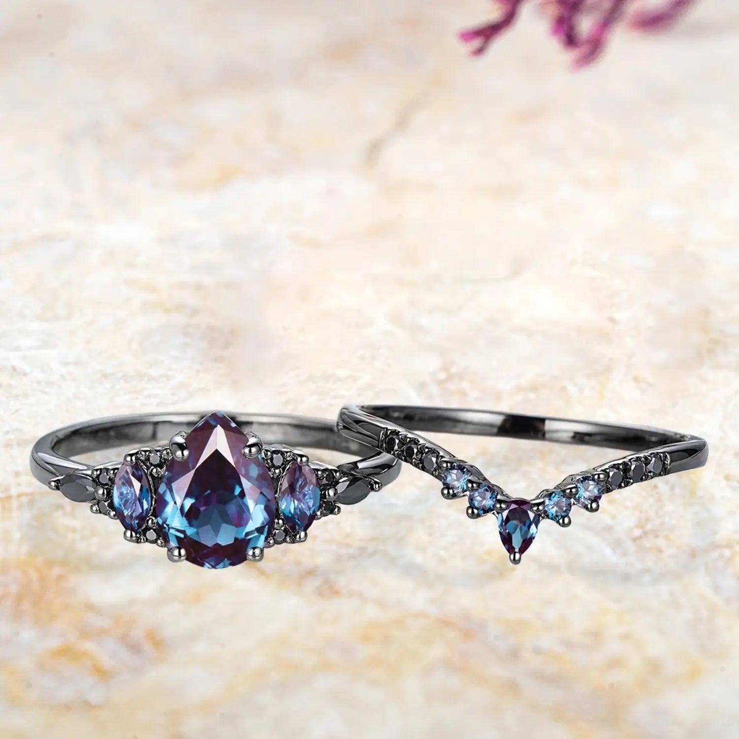 Pear alexandrite cluster engagement ring and chevron wedding band displayed separately showing June birthstone Gothic bridal set
