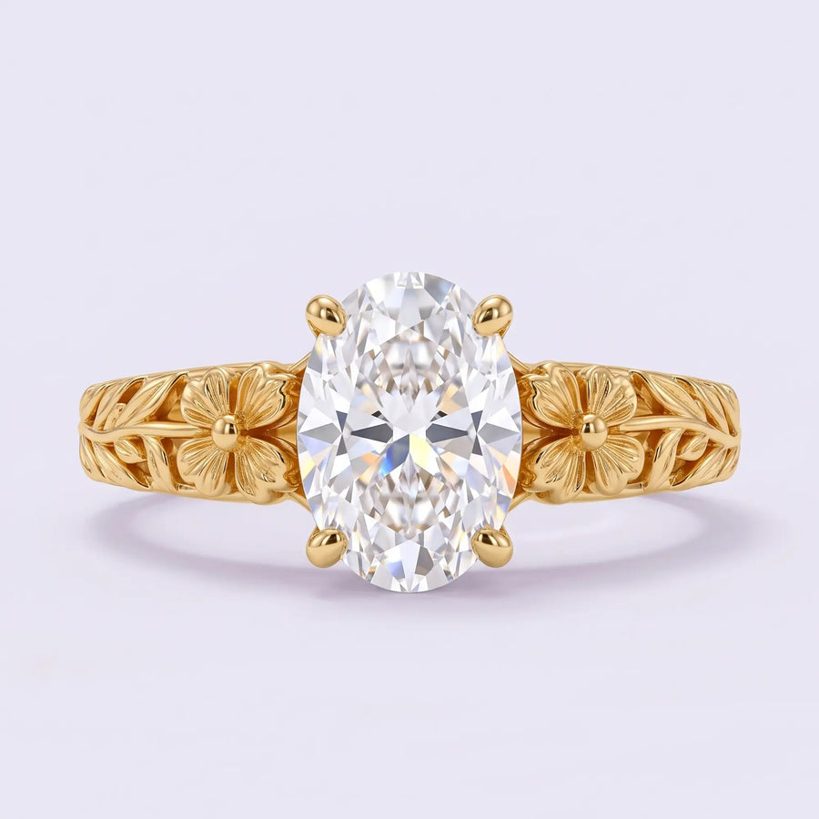 Front view of Avelune floral solitaire engagement ring showing an oval lab diamond between matching gold flowers and leaf shoulders.
