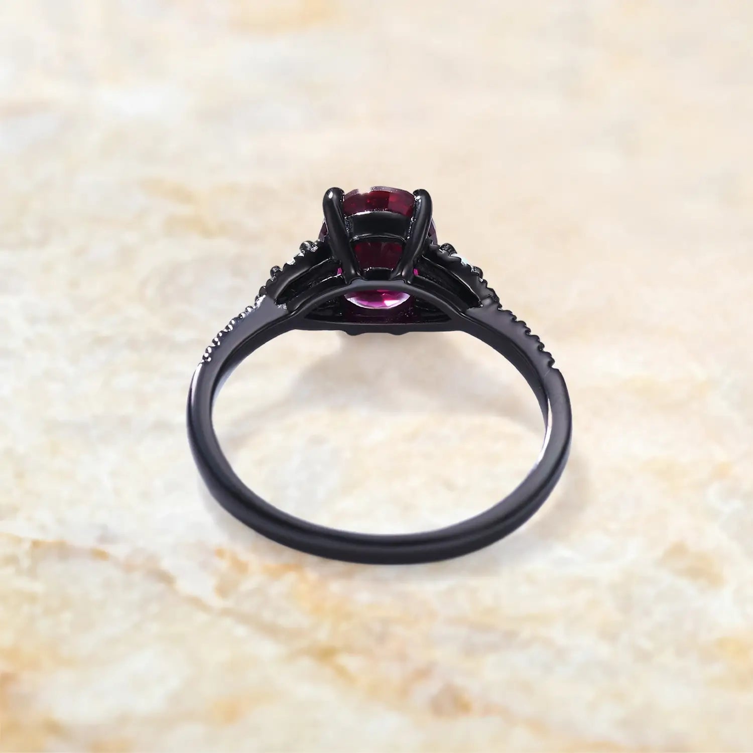 Back view of garnet engagement ring showing black gold band and prong setting