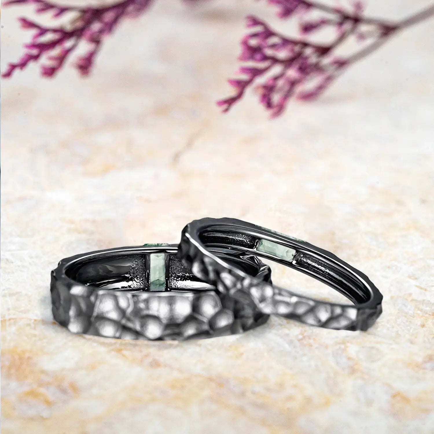 His and hers moss agate rings displayed separately showing Gothic hammered black gold couple wedding bands