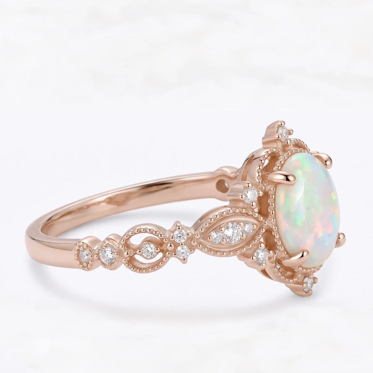 Right side view of Iravelle Edwardian oval opal engagement ring showing the decorative gold scrollwork, symmetrical openwork and gemstone profile.