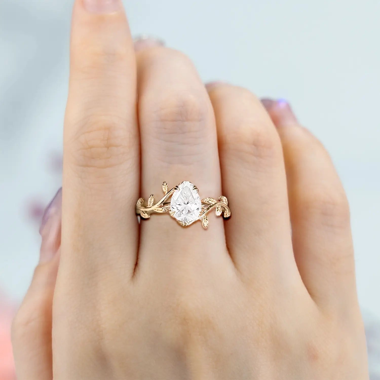 moissanite-engagement-ring-on-hand-yellow-gold-nature-inspired-leaf-design