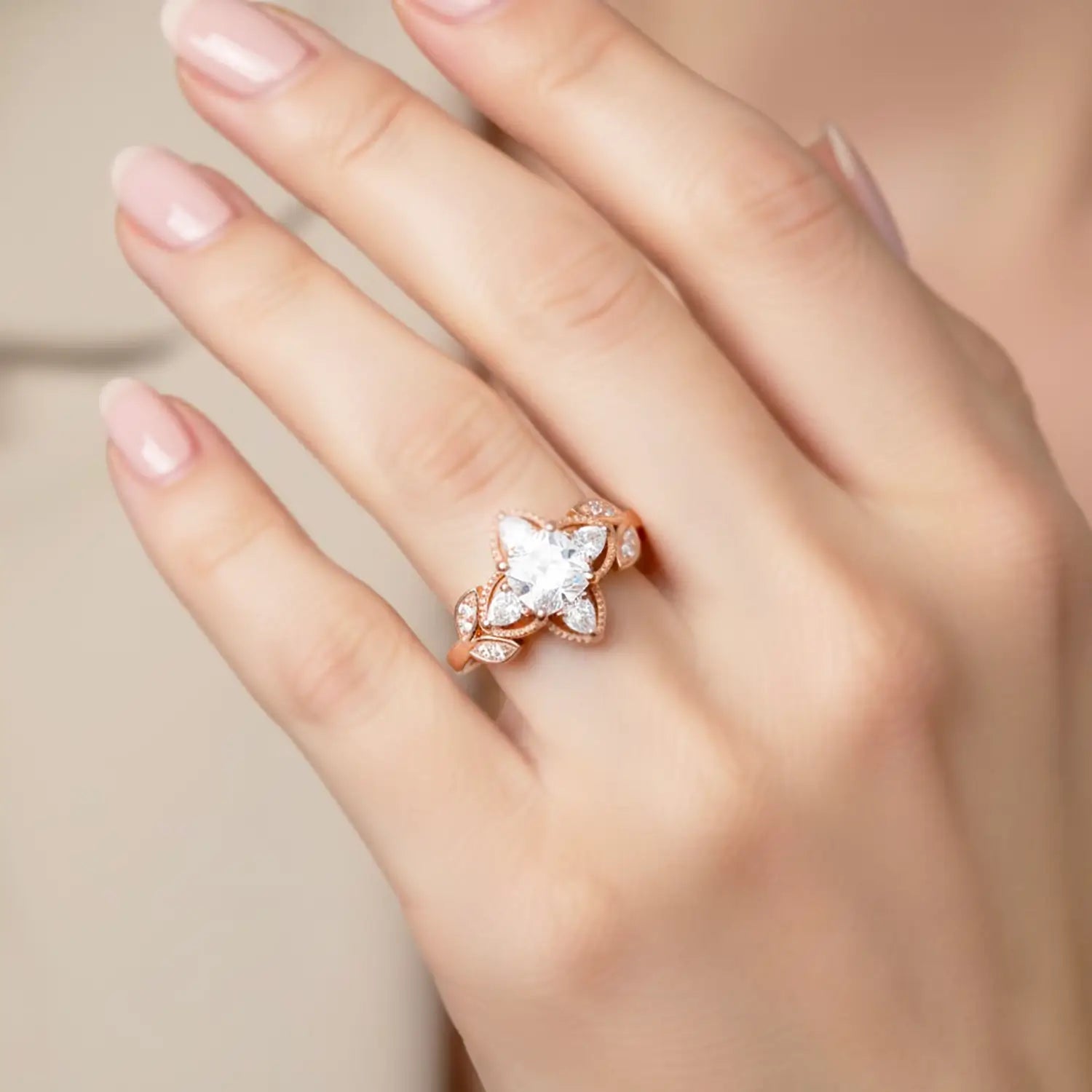 Woman wearing cushion moissanite engagement ring with four leaf clover pear halo in rose gold