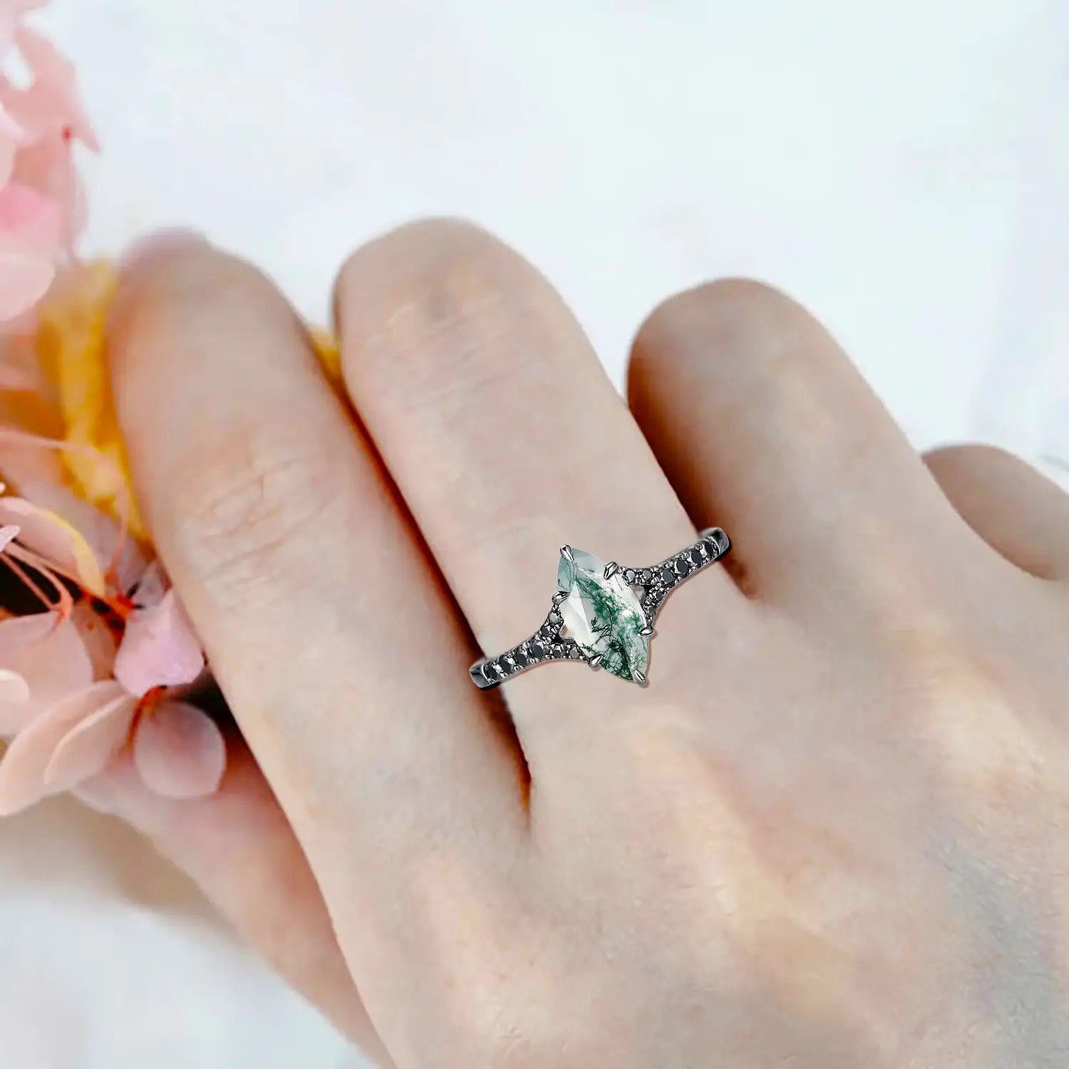 Woman wearing marquise moss agate engagement ring with split shank and black moissanite pavé in black gold