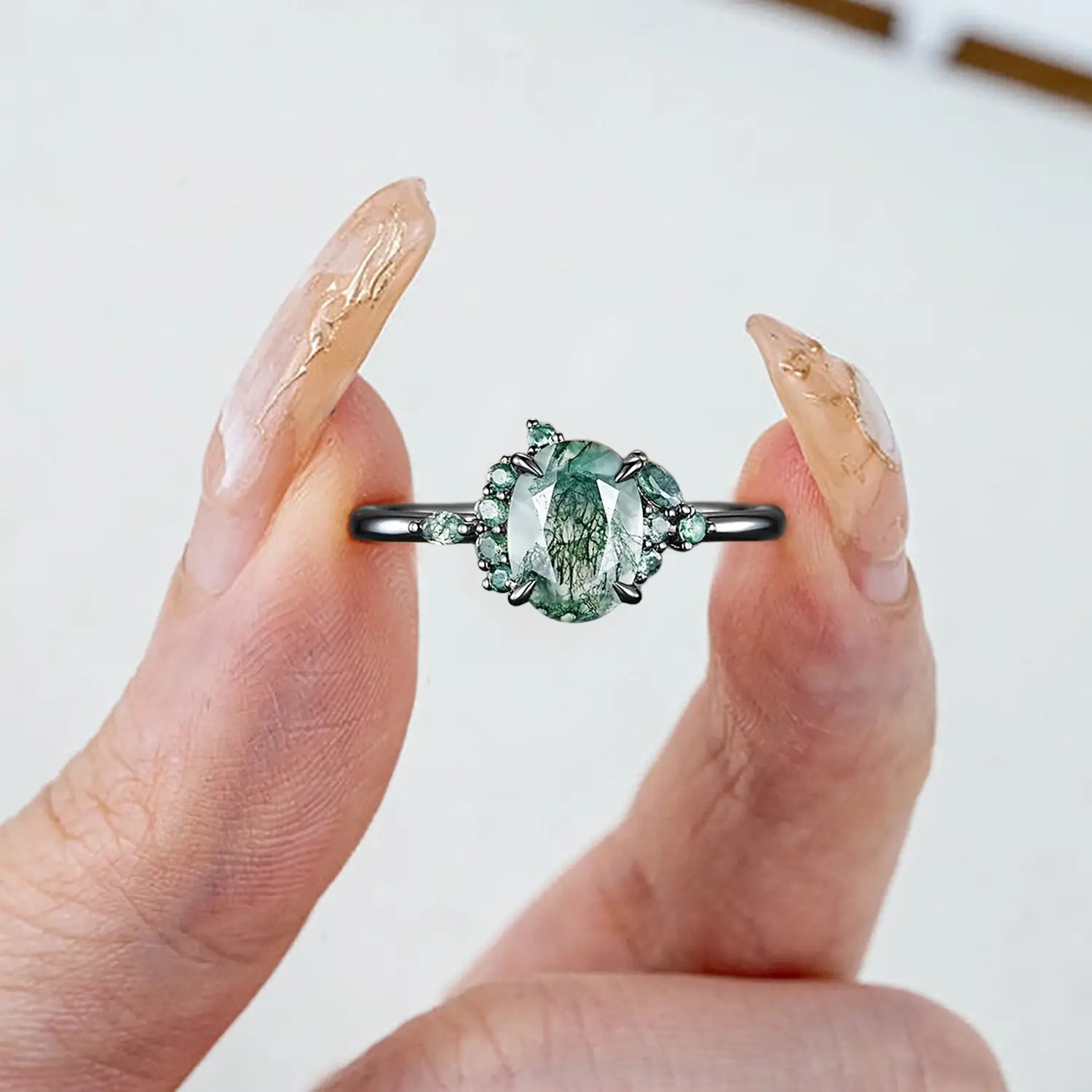 Woman wearing oval moss agate Gothic engagement ring black gold claw setting